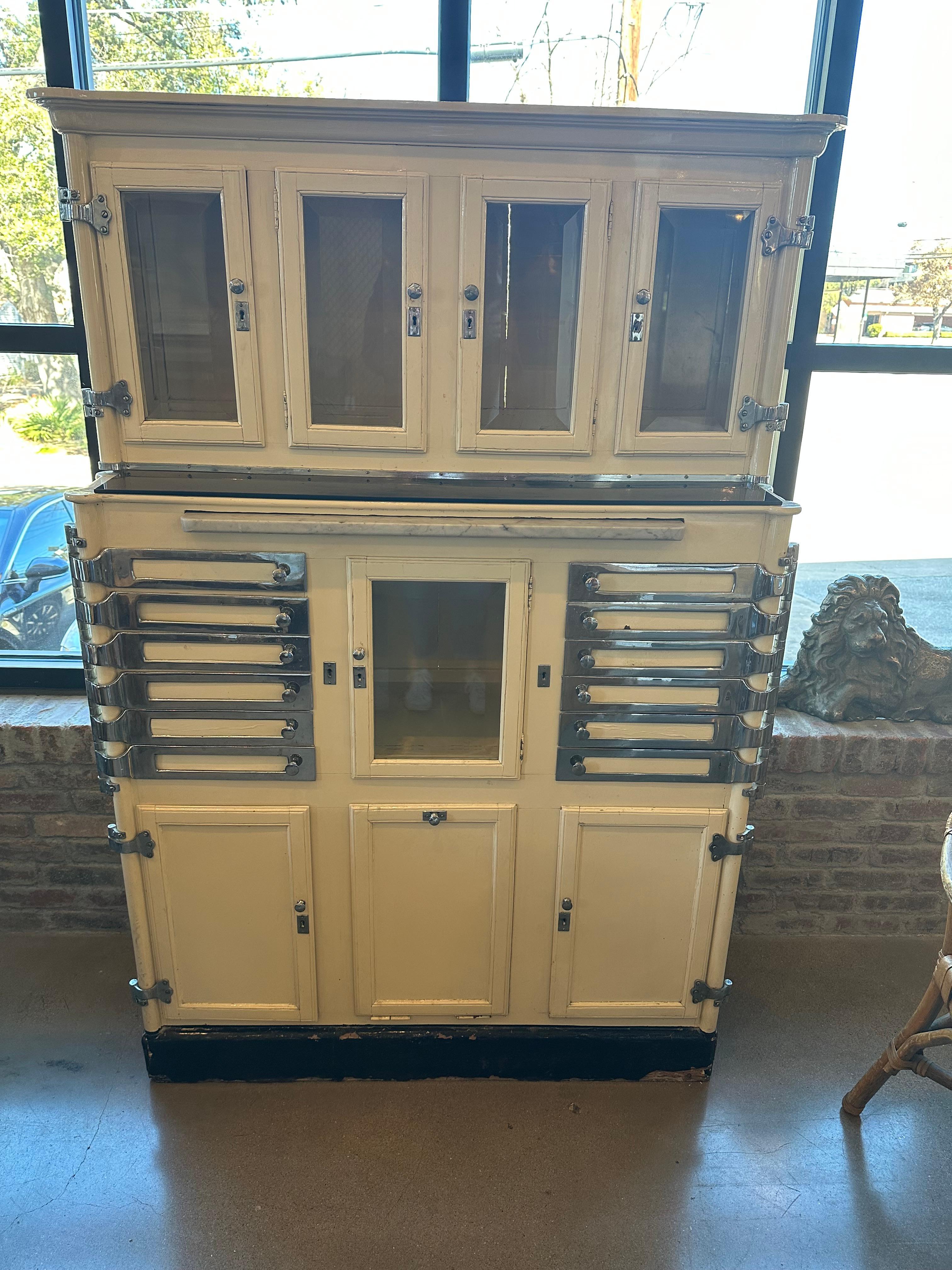 Authentic medical or dental cabinet in cream lacquer wood case with polished steel and nickel hardware. Swivel metal drawers and beveled glass doors make charming storage. Attributed to Lee Smith & Sons, makers of Aseptic dental cabinets. 1920s.