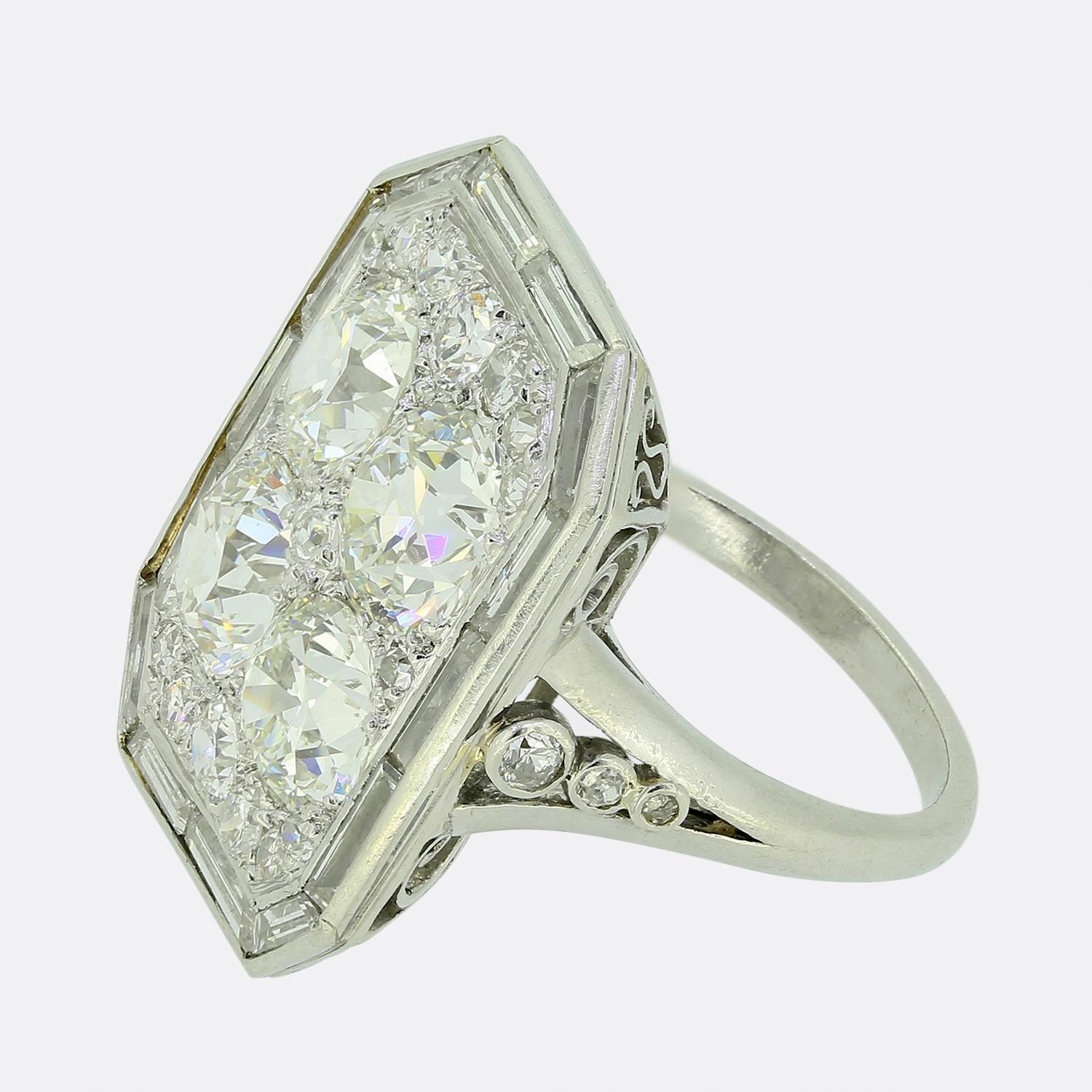Here we have a truly stunning tablet ring taken from the early stages of the 20th century. This captivating piece features four prominent round faceted old mine-cut diamonds at the centre of of the face, exuding radiance and charm; these principal