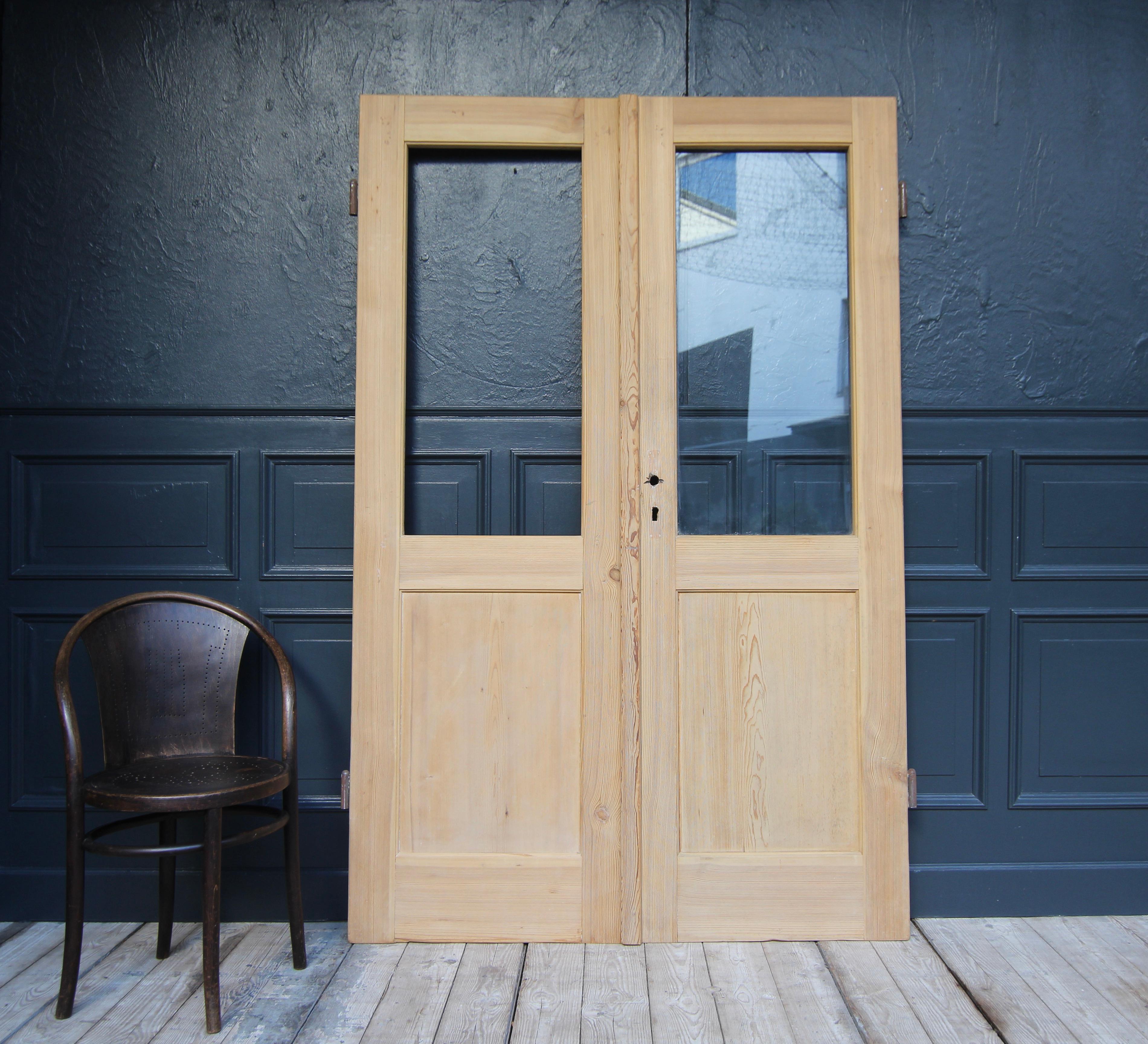 Pine wood double door from Switzerland. Early 20th century. Unrestored.

Double door consisting of two originally half-glazed doors in frame and panel construction with large external iron fittings.

Only one glass pane is still