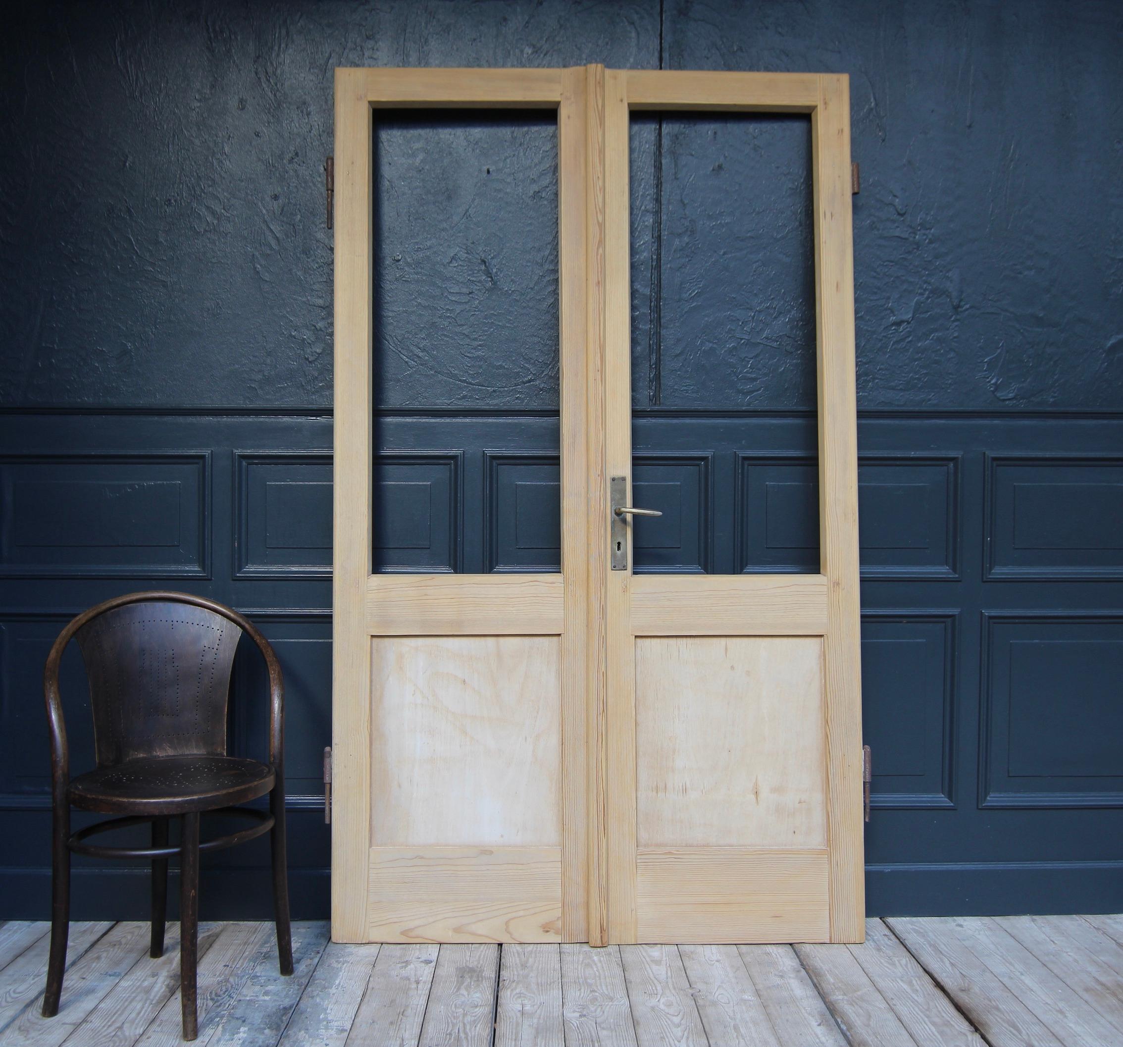 Pine wood double door from Switzerland. Early 20th century. Unrestored.

Consisting of two originally half-glazed doors in frame and panelled construction (plywood panels) with large external iron fittings.
Without glass panes.

Dimensions: 
212 cm