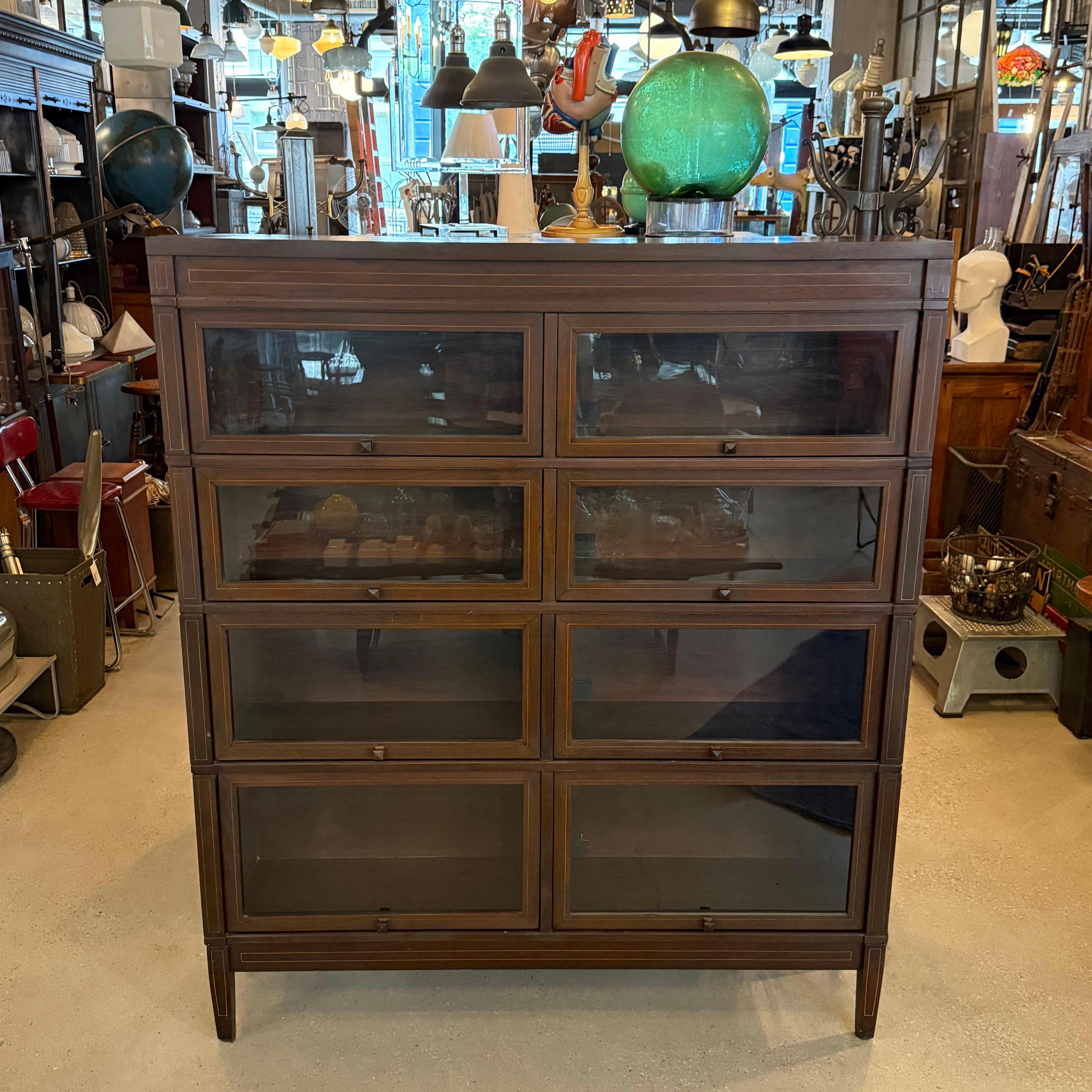 This double wide four stack mahogany barrister bookcase cabinet is attributed to The Globe Wernicke Co. circa the 1920s. This mission barrister case is a rare double wide configuration with a slim depth of 11