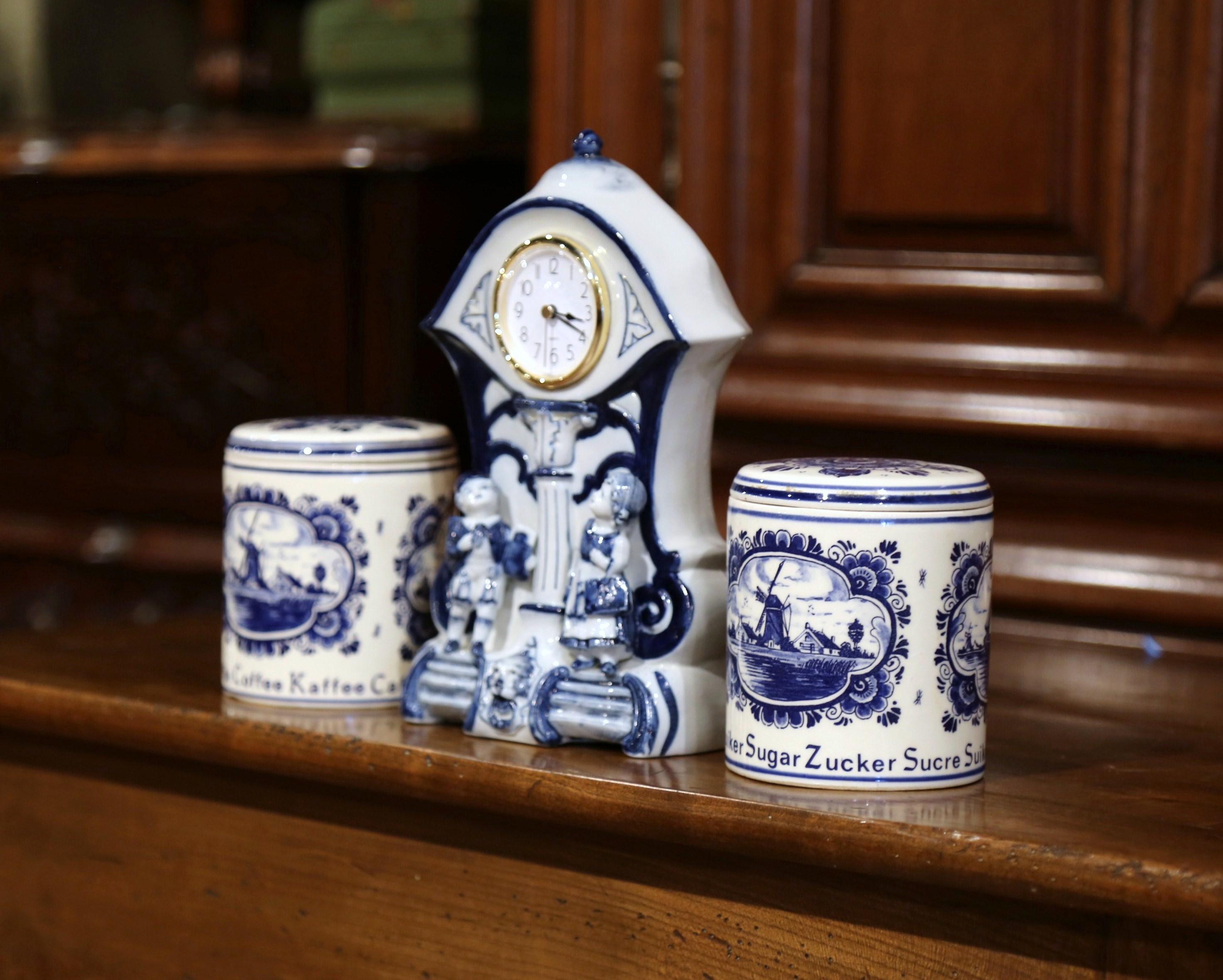 Decorate your kitchen counter with these sugar and flour ceramic canisters and a table clock; crafted in Holland circa 1920, each canister has a round lid and features blue and white floral decor with traditional sailboat and windmill. The sugar and