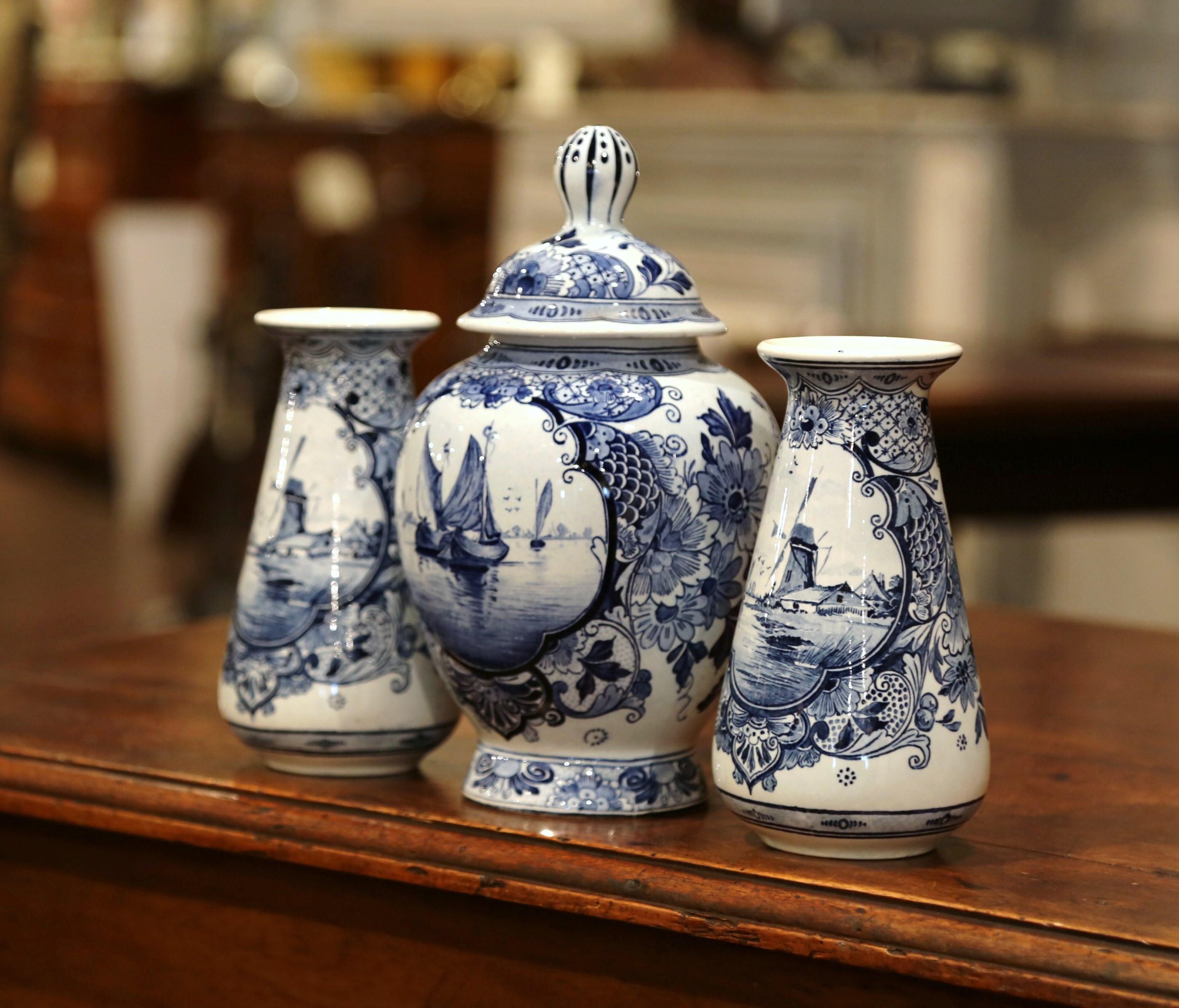 Place this elegant, three-piece set of vintage Maastricht delft porcelain on a mantle for a traditional look that will never go out of style. Created in Holland circa 1920, the ceramic set is comprised of a ginger jar and two complementary vases.