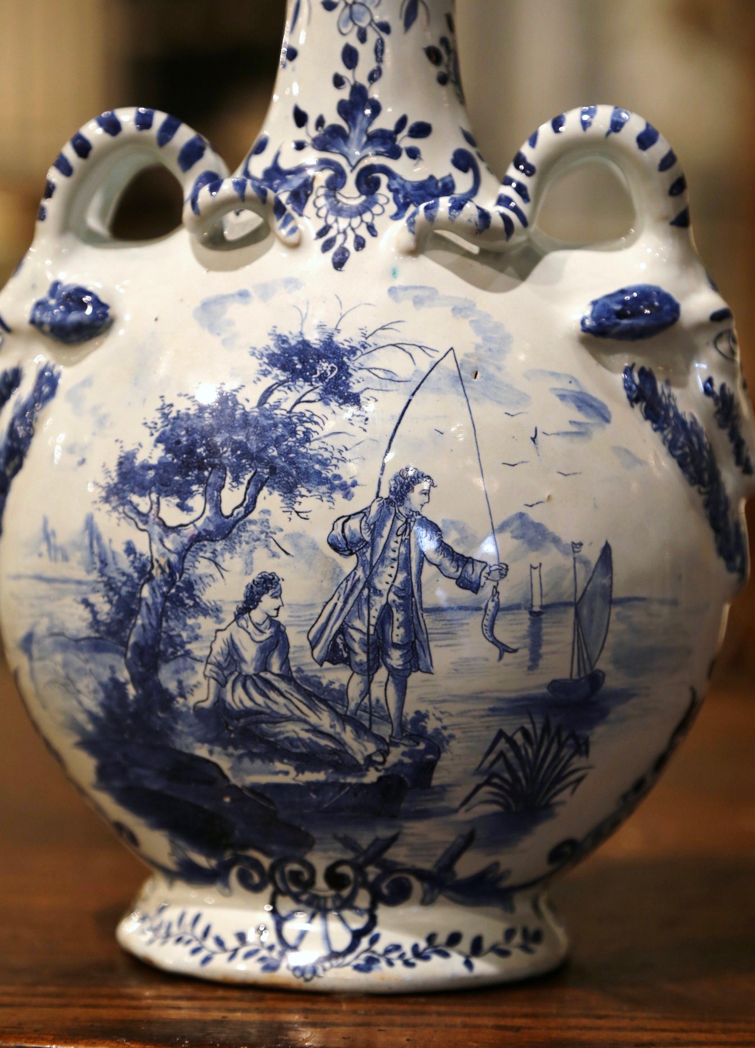 Decorate a shelf or kitchen counter with this elegant antique Delft olive oil container. Crafted in Holland circa 1920, the vase with cork top, features an intricate oval shape dressed with ram's horn side handles over a tall neck. The vessel is