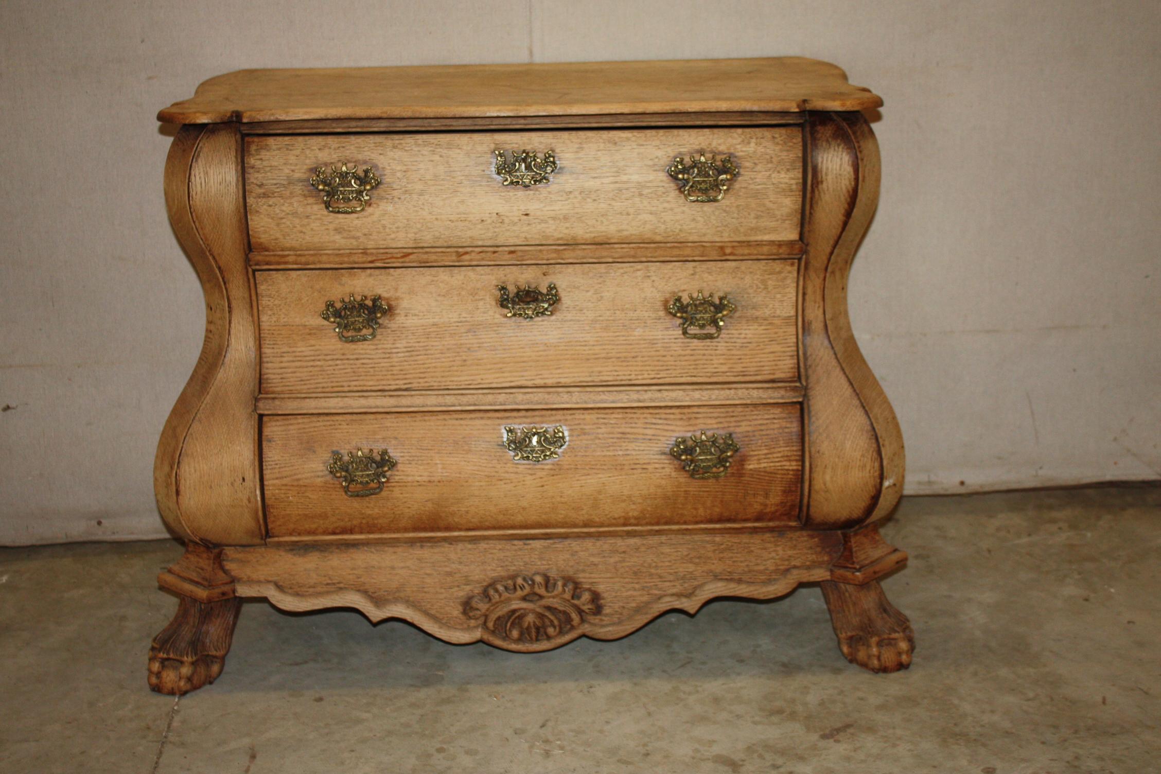 This is a very nice bleached oak Dutch Bombay commode. It dates to the early 1900s. It has ball and claw feet. It has a very nice look. The drawers work flawlessly. It is in great shape for its age.