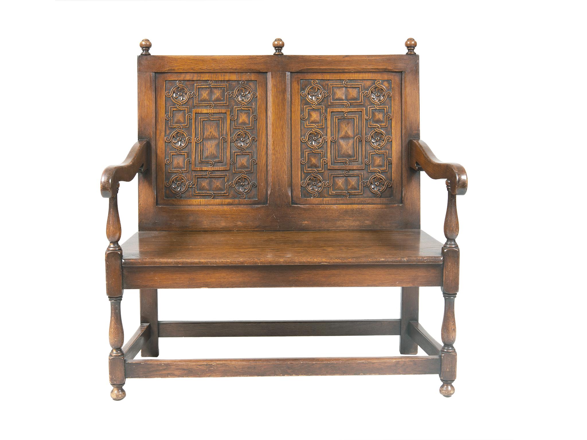 This Dutch settee was handcrafted in the late 19th-early 20th century and once furnished the New York Stock Exchange. It is comprised of oak wood with a warm red-brown tone. The wood is beautifully carved with a floral and geometric design on the