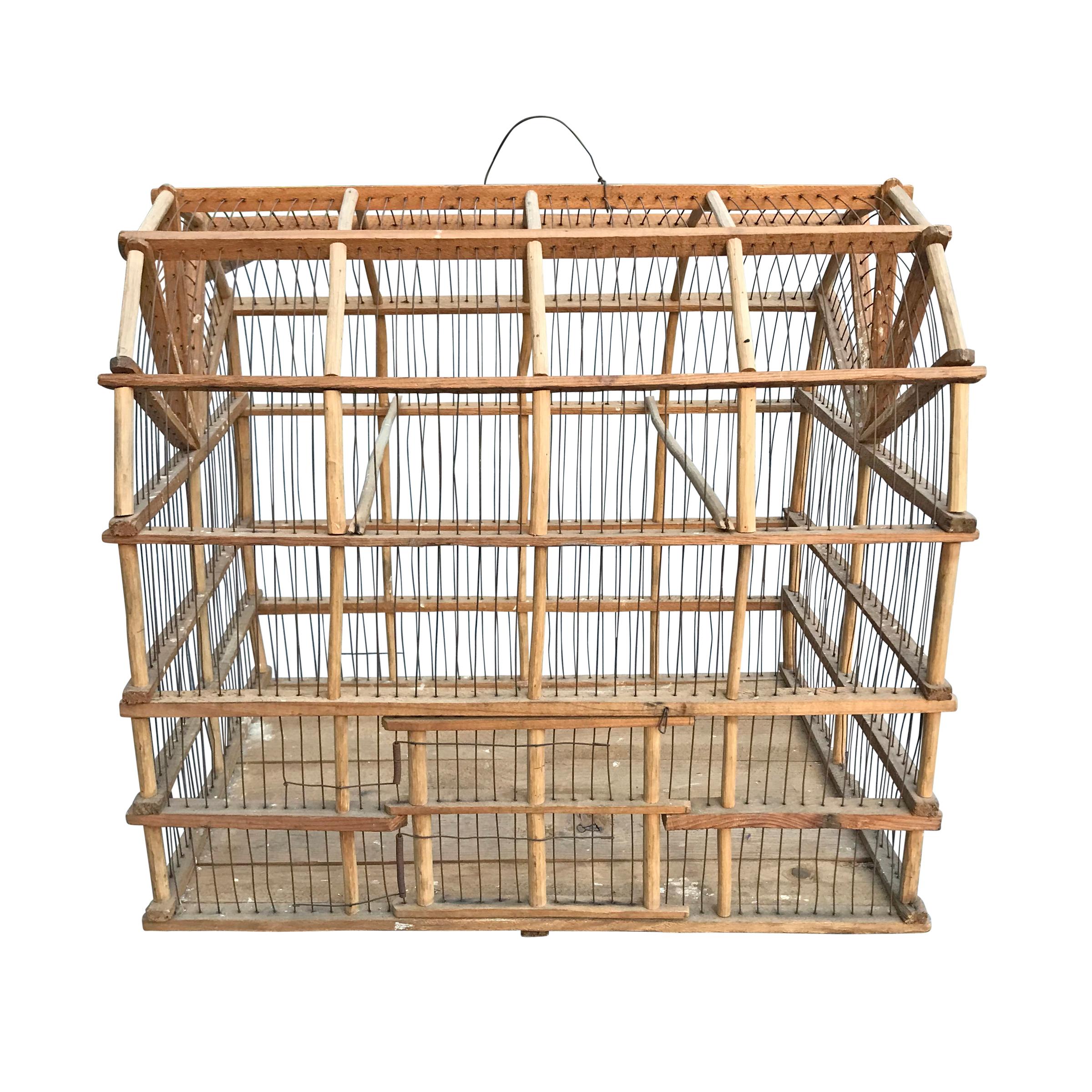 A wonderfully sculptural early 20th century American Folk Art Dutch colonial barn birdcage of timber frame construction with a tension mounted door, plank-pine flooring, and thin wire cage and handle.