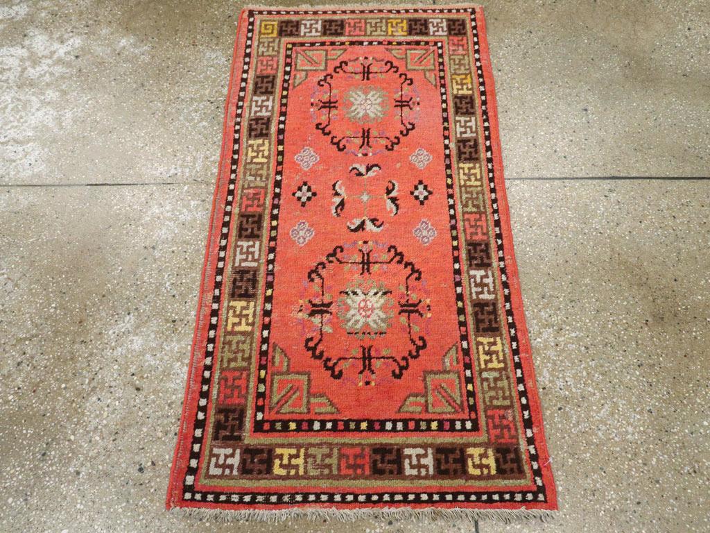 Tapis ancien du Turkestan oriental Khotan. Le champ rose saumon de cette petite dispersion vivante provenant de la ville-oasis de Khotan dans le Xinjiang présente deux octogones ajourés en brun foncé et bleu pâle, placés dans des coins triangulaires