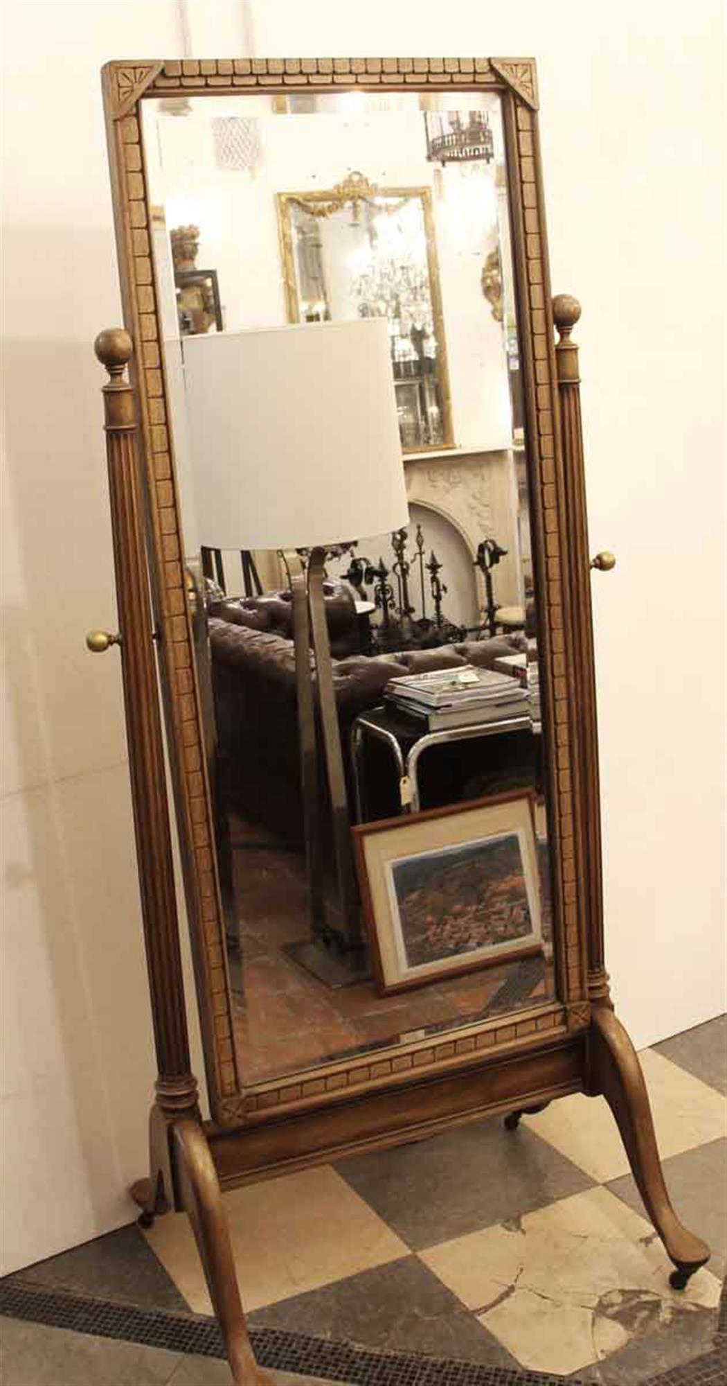 Medium wood tone cheval mirror made of fruitwood with carved details in the Eastlake manner. The decoration is geometric with floral corners with fluted column sides. Brass hardware on sides and furniture wheels. Beveled mirror with slight