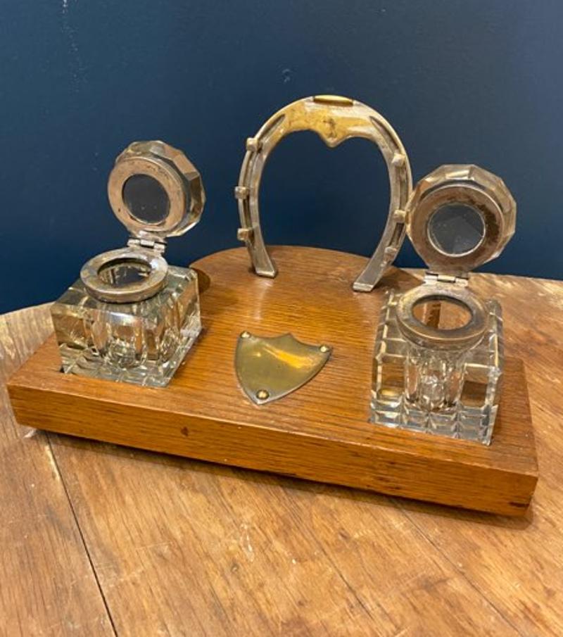 Early 20th century Edwardian double inkwell with horseshoe pen holder
This double inkwell desk set has two glass inkwells that sit upon a wooden base with an attached horseshoe that acts as a pen holder. Perfect for the equestrian lover or writer