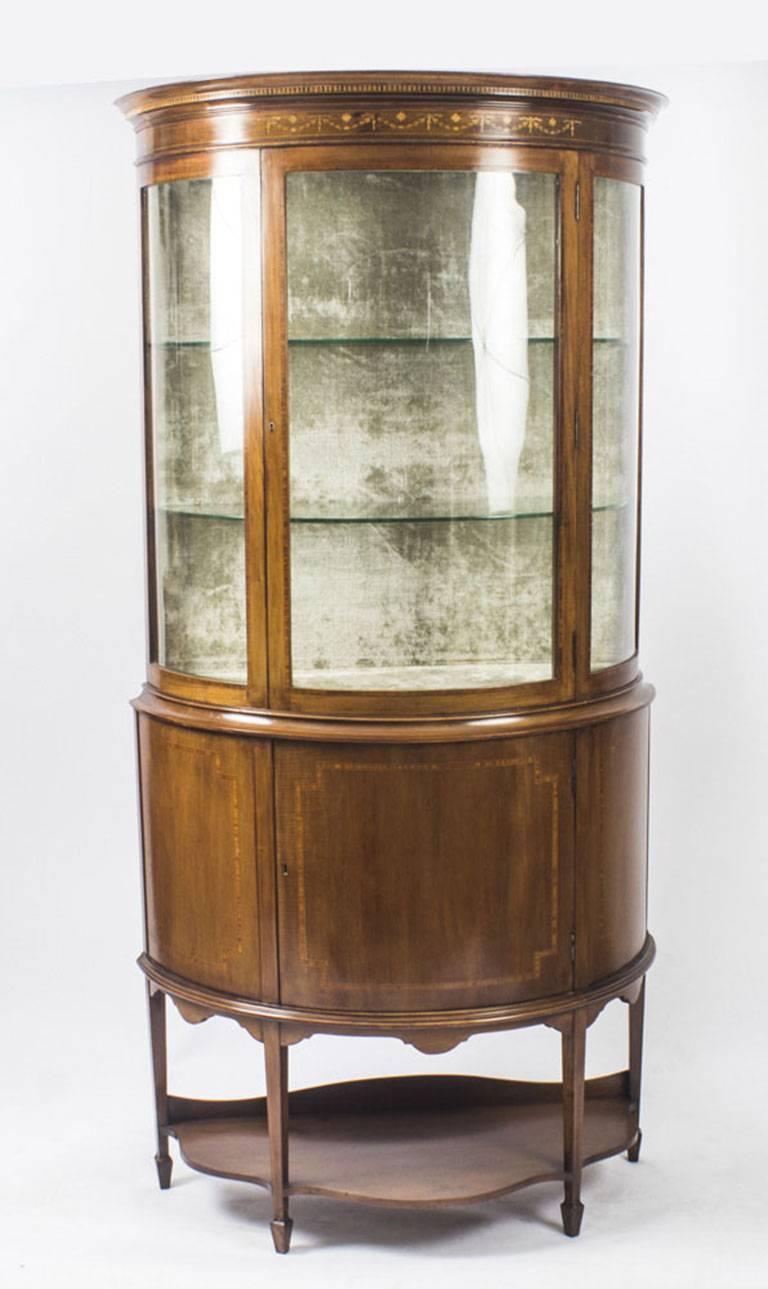 A stunning Antique English Edwardian mahogany half moon glazed display cabinet, Circa 1900 in date.

The top has a large central door with bow glazing flanked by bow glass on each side. The interior has two shelves and has been lined in sumptuous