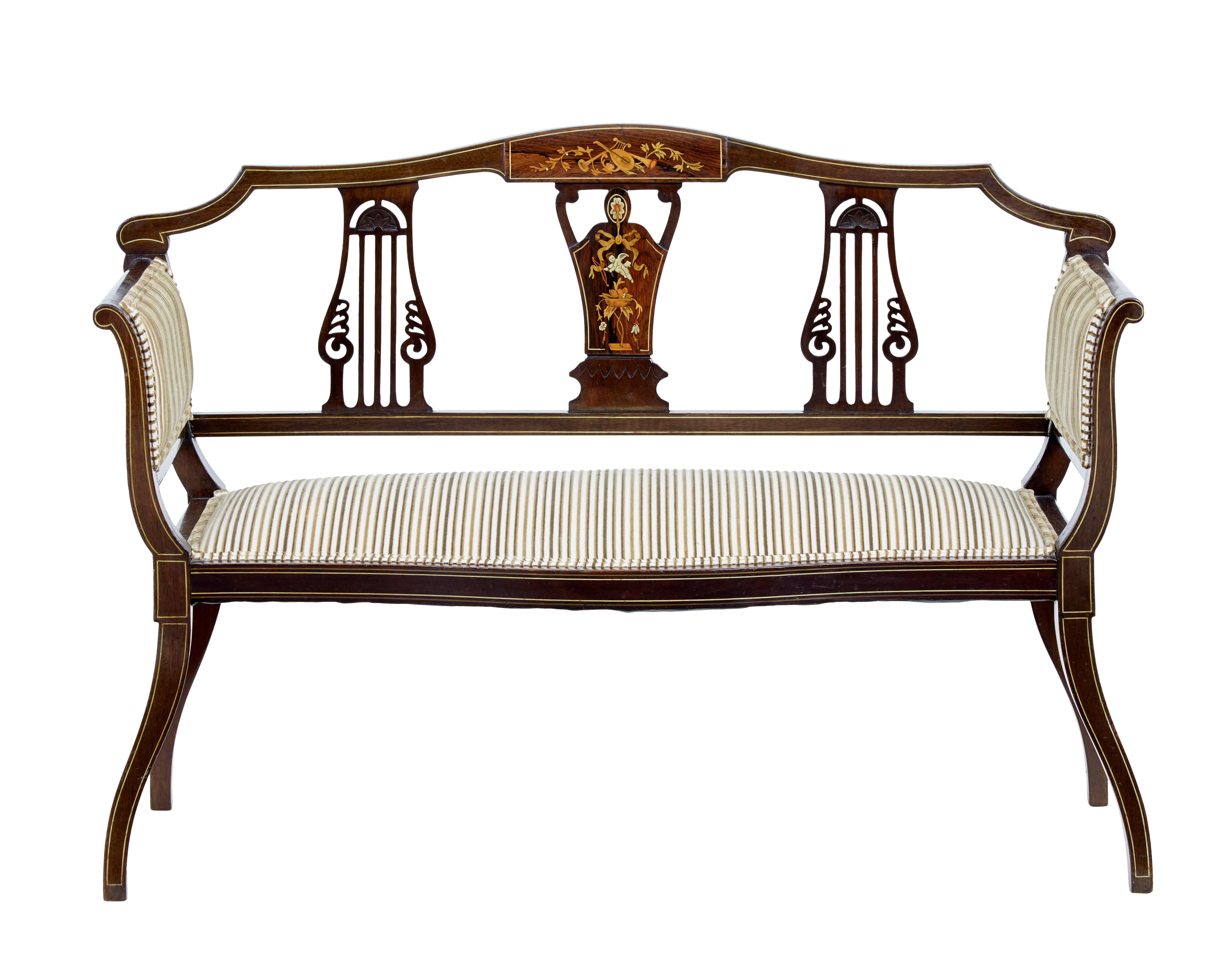 Petit Edwardian salon sofa, circa 1910.

Open back sofa featuring an inlaid backrest. Inlay shows musical instruments, cherub and swags.

Later upholstery in good condition.

Minor surface marks to woodwork.