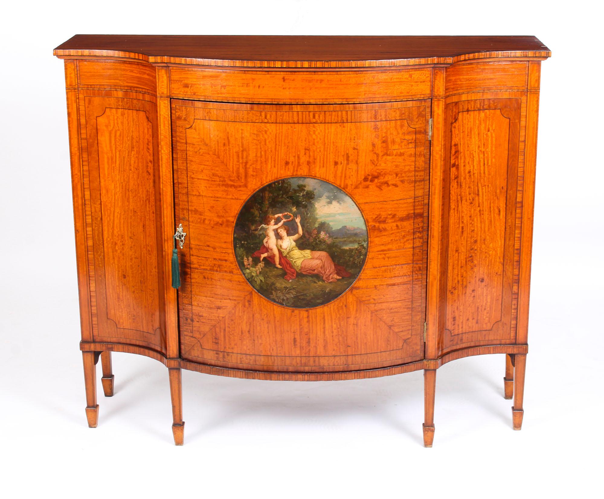 This is a truly stunning English Edwardian hand painted and inlaid shaped satinwood sideboard, circa 1900 in date.
 
This splendid crossbanded cabinet is made of the finest quality satinwood with a striking flame effect and ebony stringing. 
