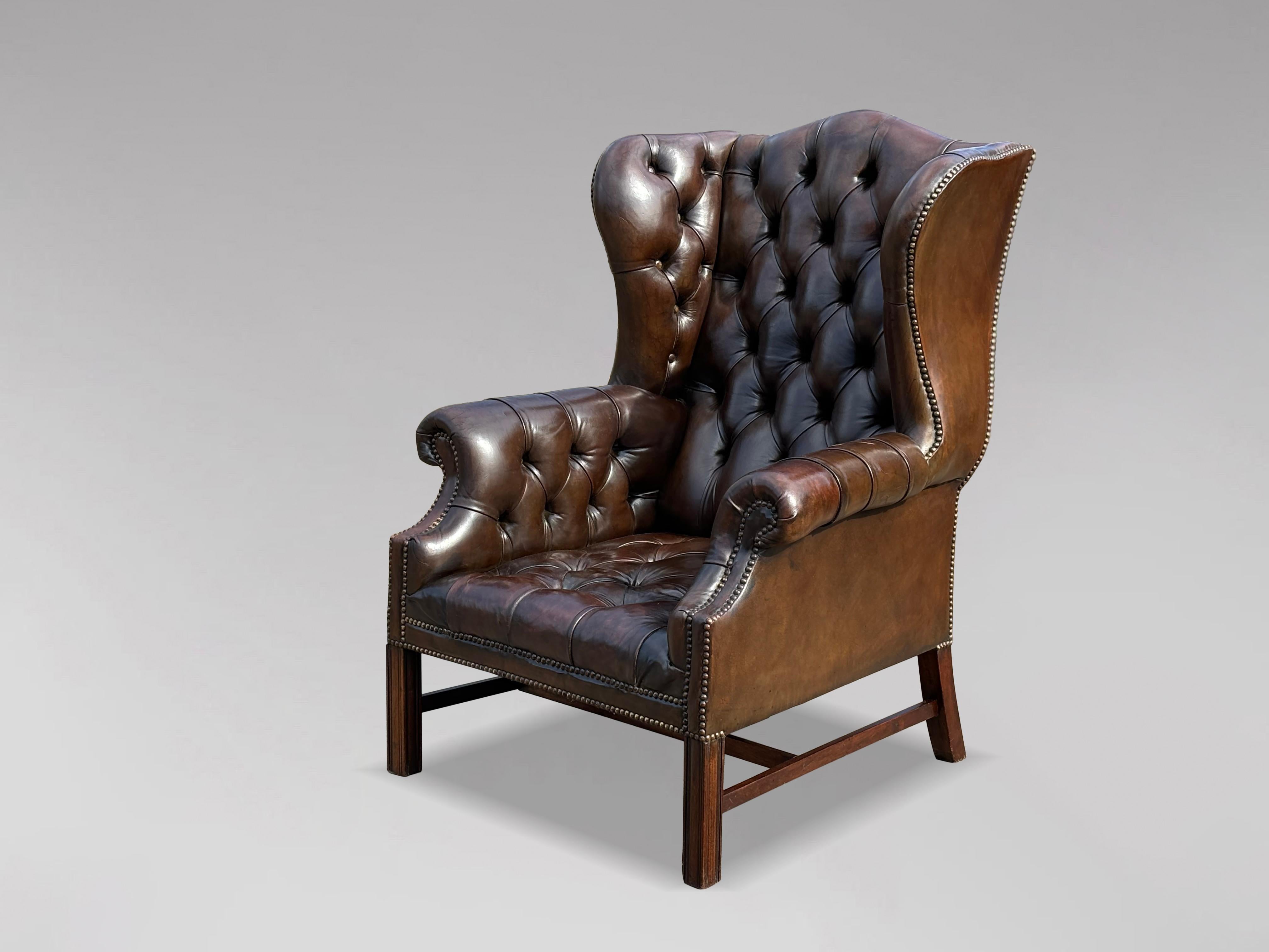Fauteuil à oreilles en cuir marron à boutons pleins, de style George III, de grande qualité, datant du début du 20e siècle et de l'époque édouardienne. Le cadre substantiel et bien formé est doté d'une assise, d'un dossier et d'accoudoirs