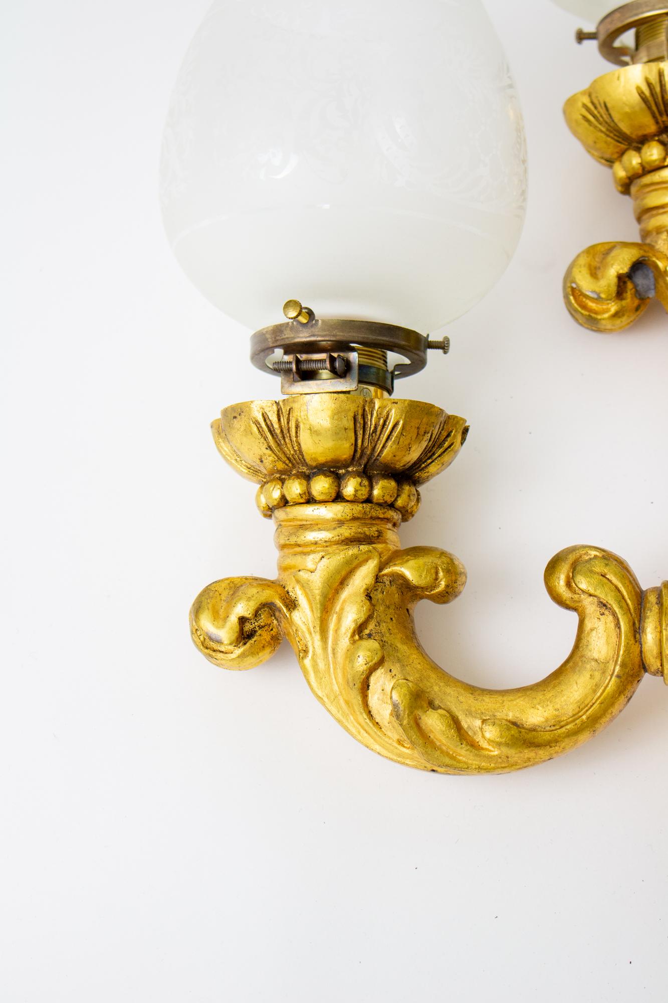 Early 20th Century E.F.Caldwell italianate gilt bronze sconces, a pair. Heavy gilt brass casting with a round backplate. Single upcurved arm with a foliate pattern. Etched glass shade. Original finish is in good condition. Surface cleaned and