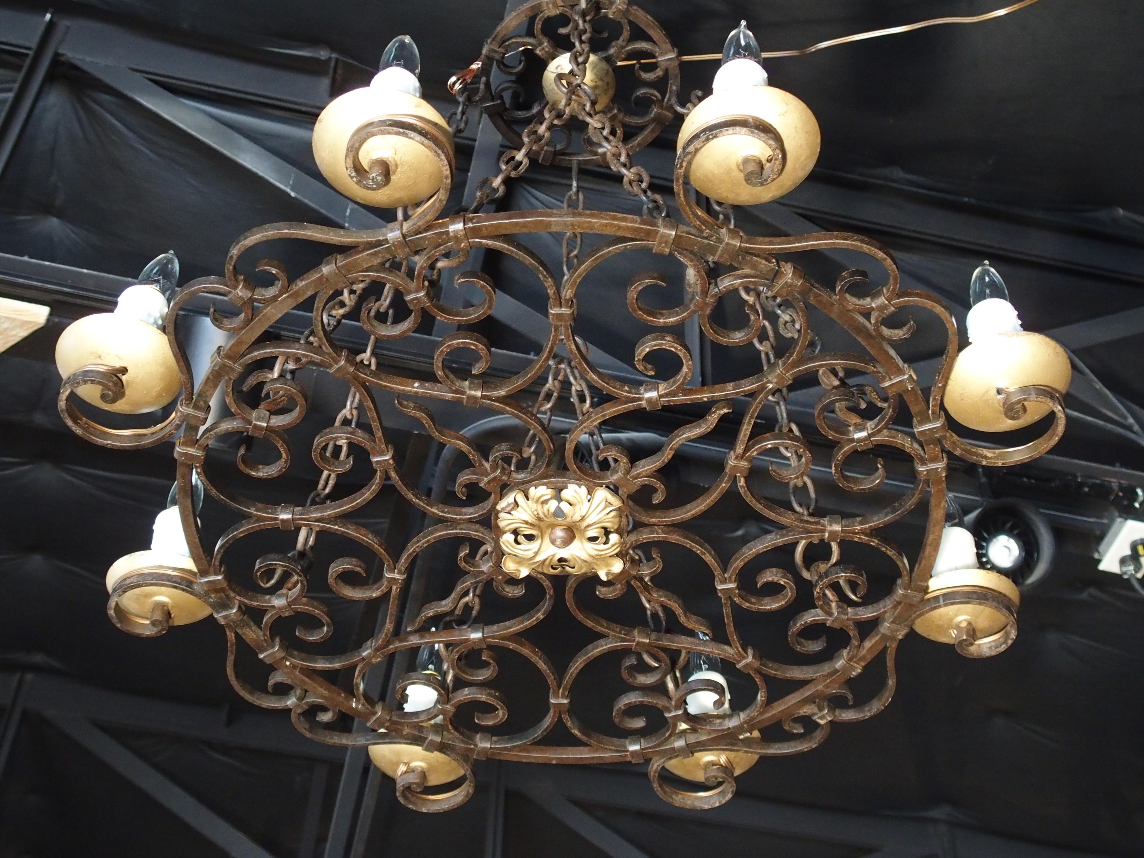 This attractive French iron chandelier is composed of 8 raised S-scroll motifs holding lights around its perimeter. Its central flat scrolling surface is ornamented with C-scrolls, oblong circles, and S-scrolls, with a gilt metal floret center