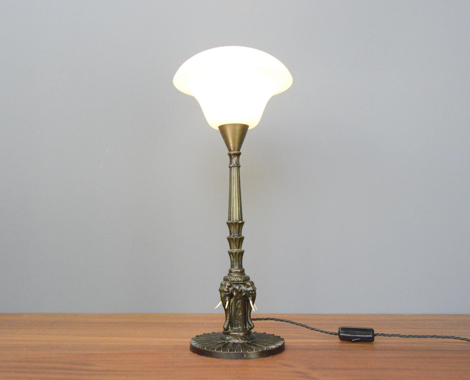 Early 20th century elephant table lamp

- Aged bronze body with cast iron Elephant heads x3
- Takes E27 fitting bulbs
- Opaline glass shade
- On/Off toggle switch on the cable
- Danish ~ 1910
- 52cm tall x 24cm wide 

Condition