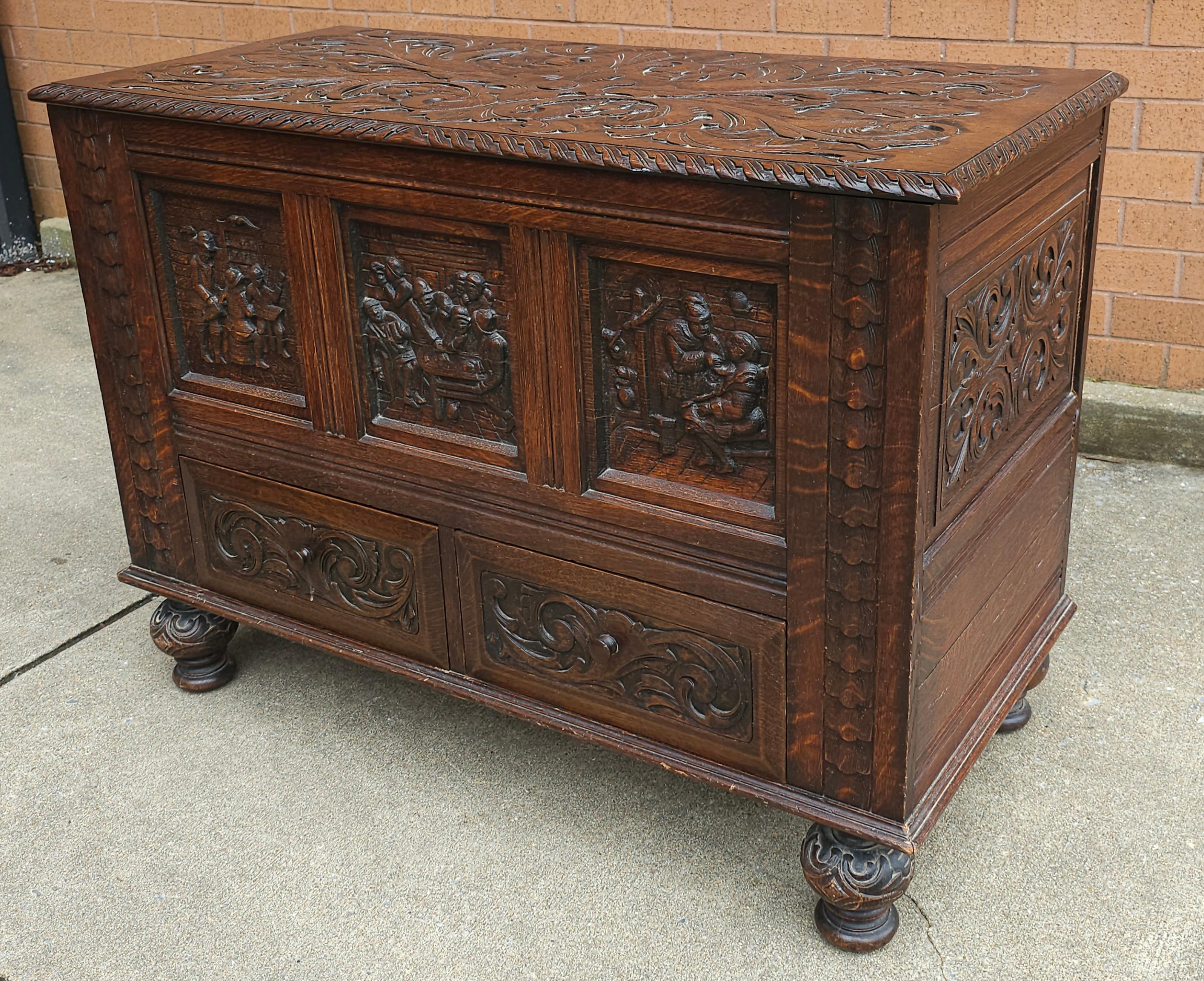 An Early 20th Century Elizabethan Style Hand-Carved Oak Storage / Blanket Chest. Intricately hand carvings of floral and figural scenes. Measures 42