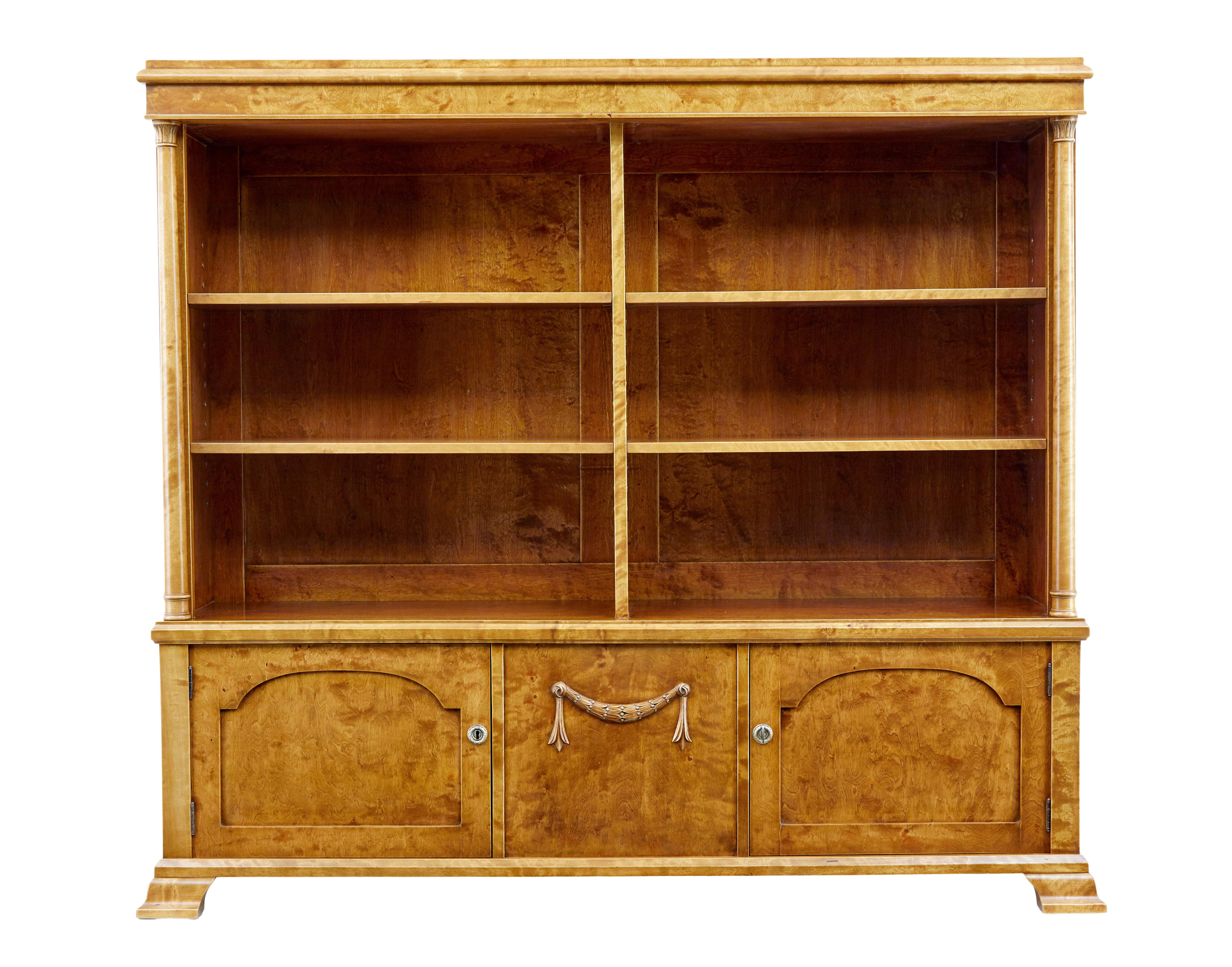 Schönes offenes Bücherregal aus reicher Birke, um 1910.

Vier verstellbare Einlegeböden mit einer zentralen Trennwand, darunter eine zentrale Platte mit geschnitzten applizierten Swag, flankiert von je einem eintürigen Schrank.

Die gedrehten Säulen