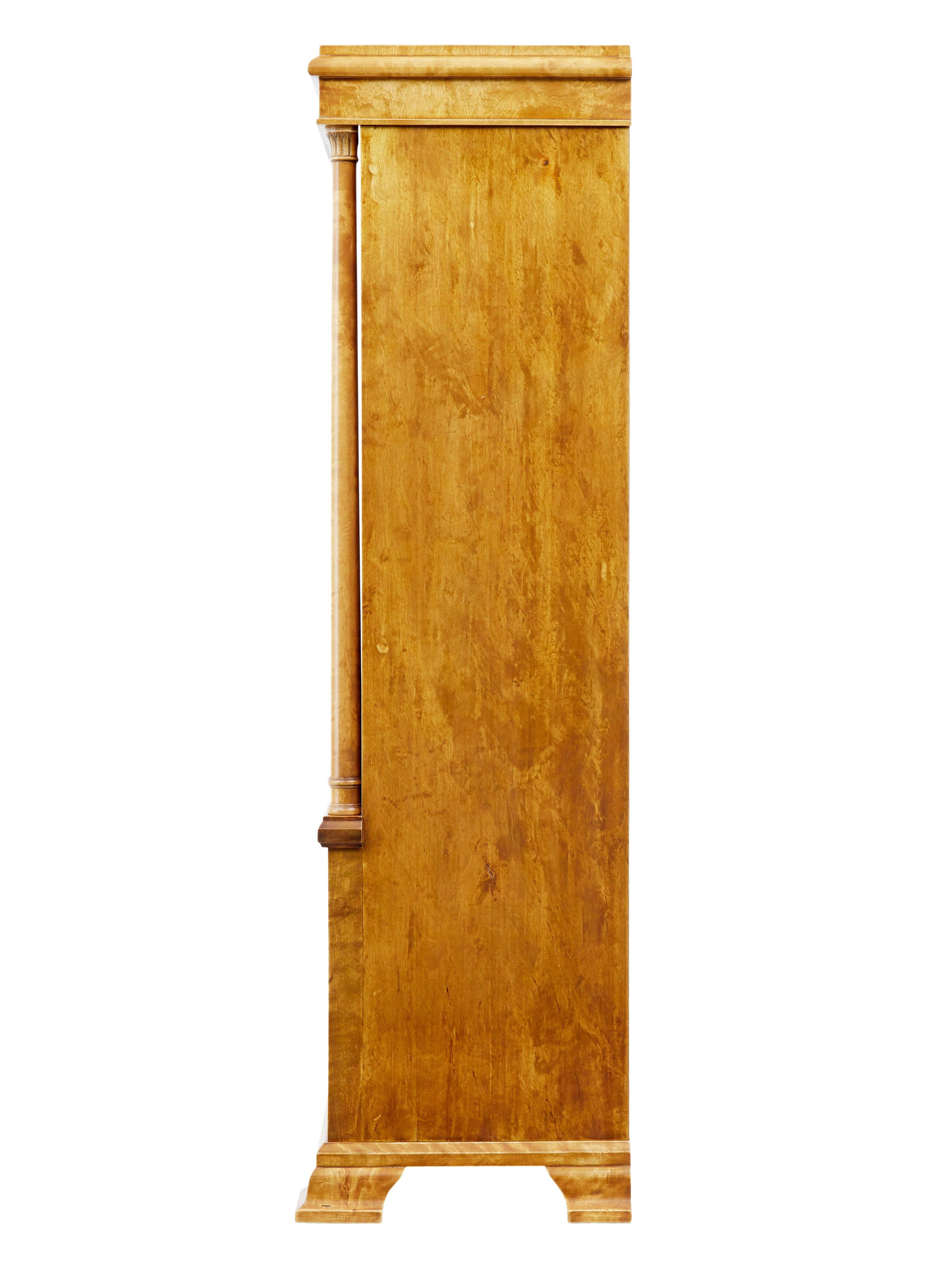 Magnifique bibliothèque ouverte en bouleau, vers 1910.

Quatre étagères réglables avec une cloison centrale, sous un panneau central avec une guirlande appliquée sculptée, flanquée de chaque côté d'une armoire à une porte.

Des colonnes tournées