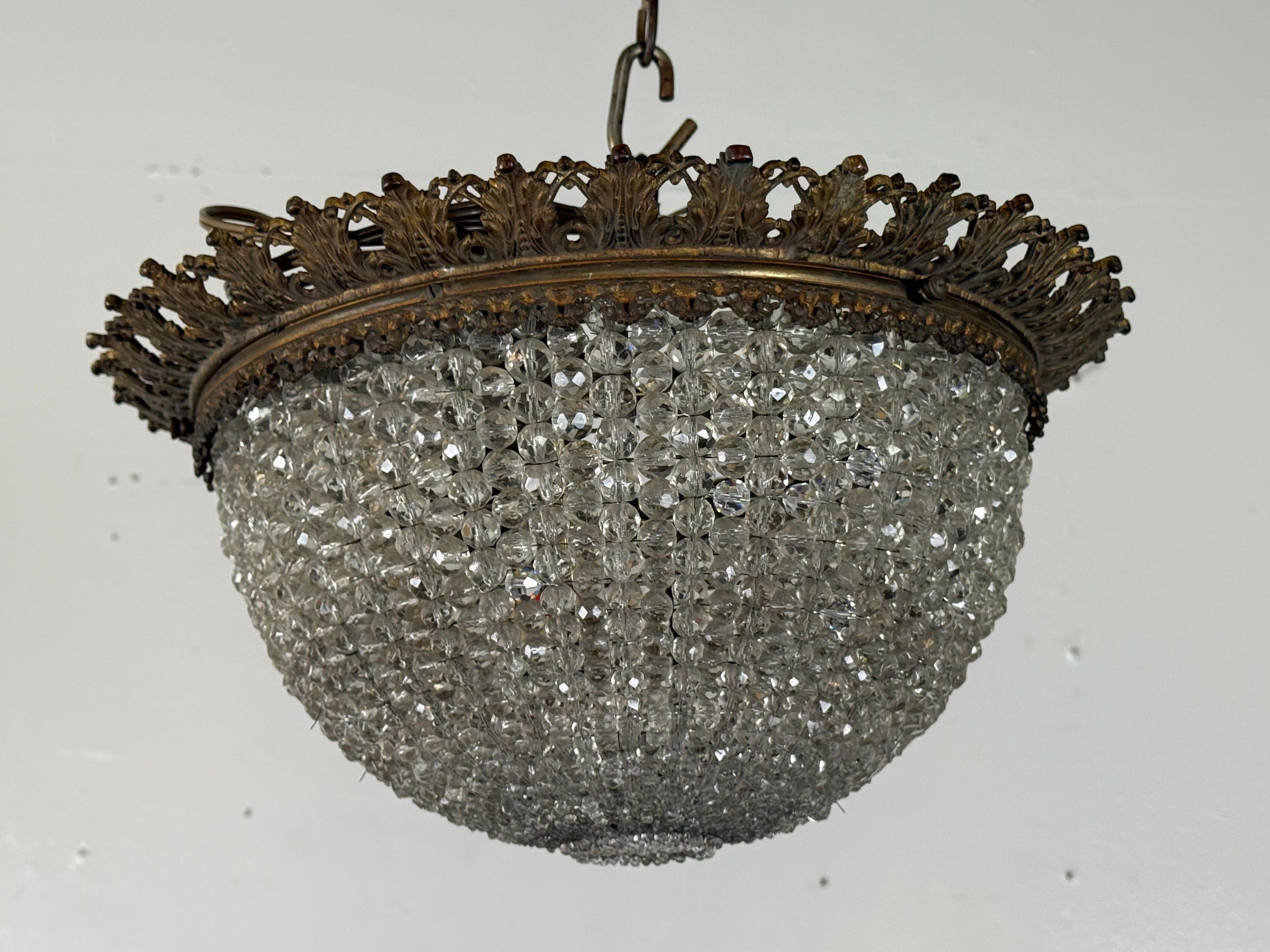 Un raffinato lampadario a cesto di cristallo in stile Impero con cornice in bronzo, con una galleria di foglie traforate che circonda il bordo superiore. Il corpo a cupola è composto da perline di cristallo sfaccettato strettamente infilate a mano