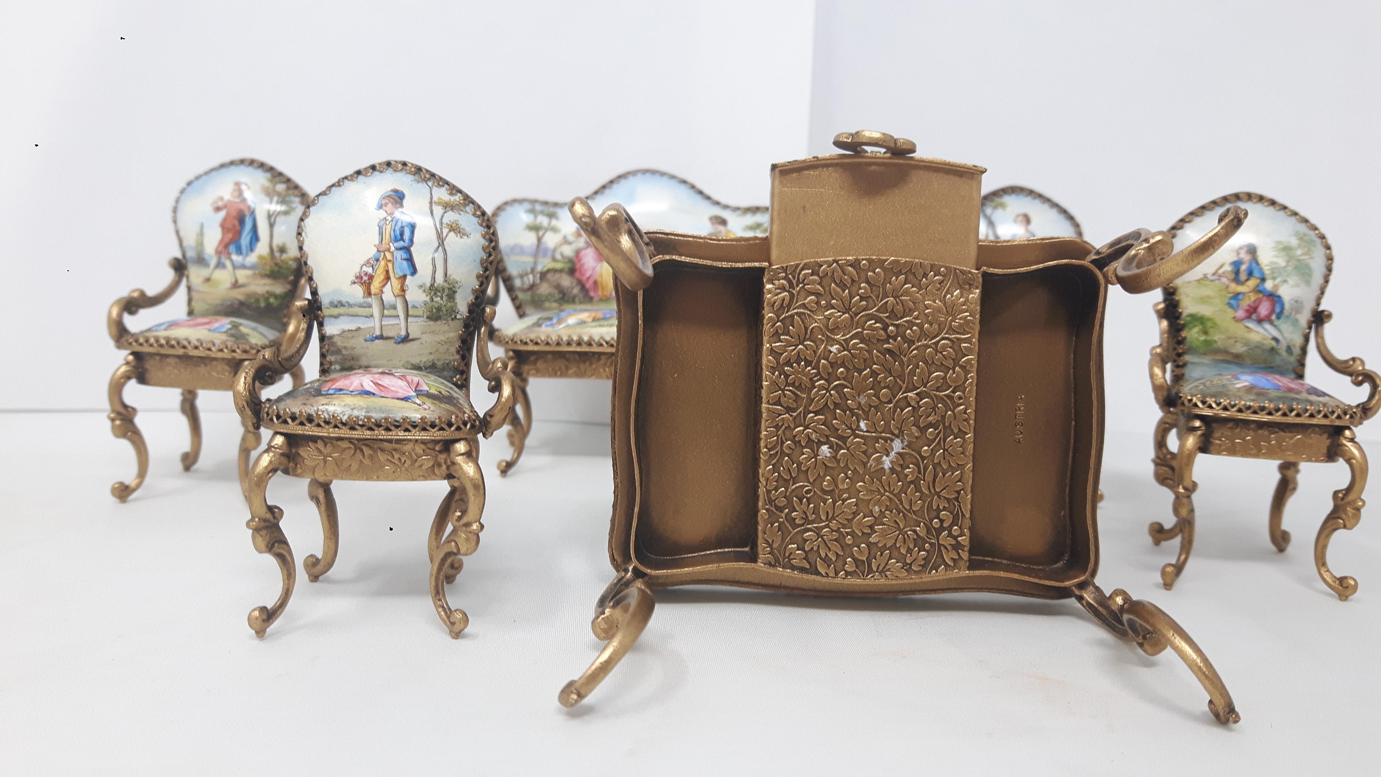 Emaille-Puppenhausmöbel, bestehend aus Tisch, Sofa und vier Stühlen, verziert mit einzelnen Figuren und romantischen Szenen.