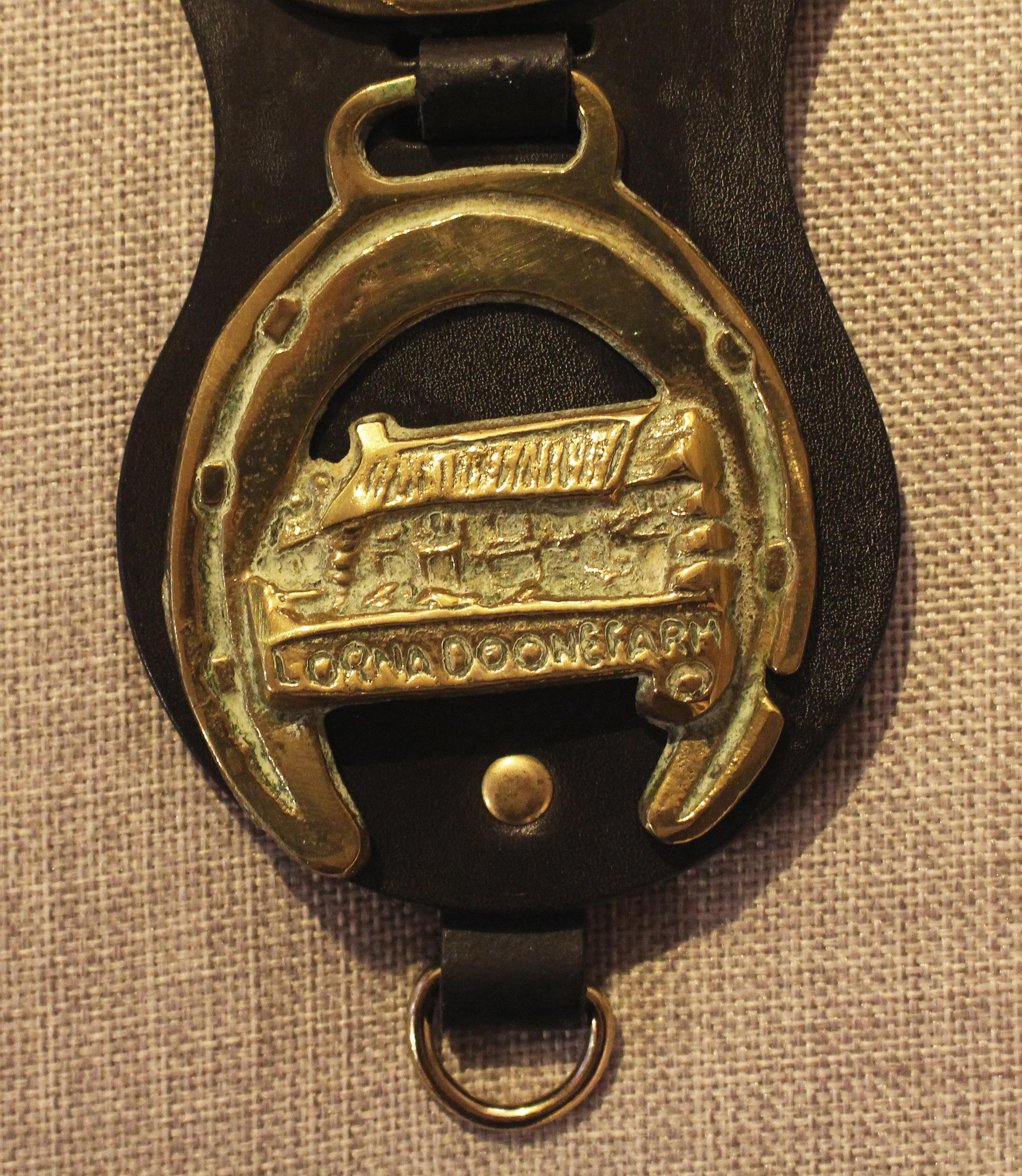 Early 20th century English 4-brass leather horse strap. Shaped leather featuring brasses of a Rampant Horse, Dray Horse, Cat, & 