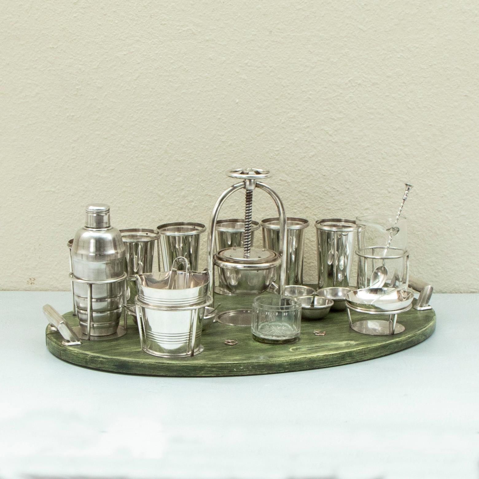 Originally used to serve cocktails on a yacht in the 1930's, this English Art Deco period silver plate bar service is supported by a green tinted wooden tray with silver handles on each end. The service includes six cups, a cocktail shaker, an ice
