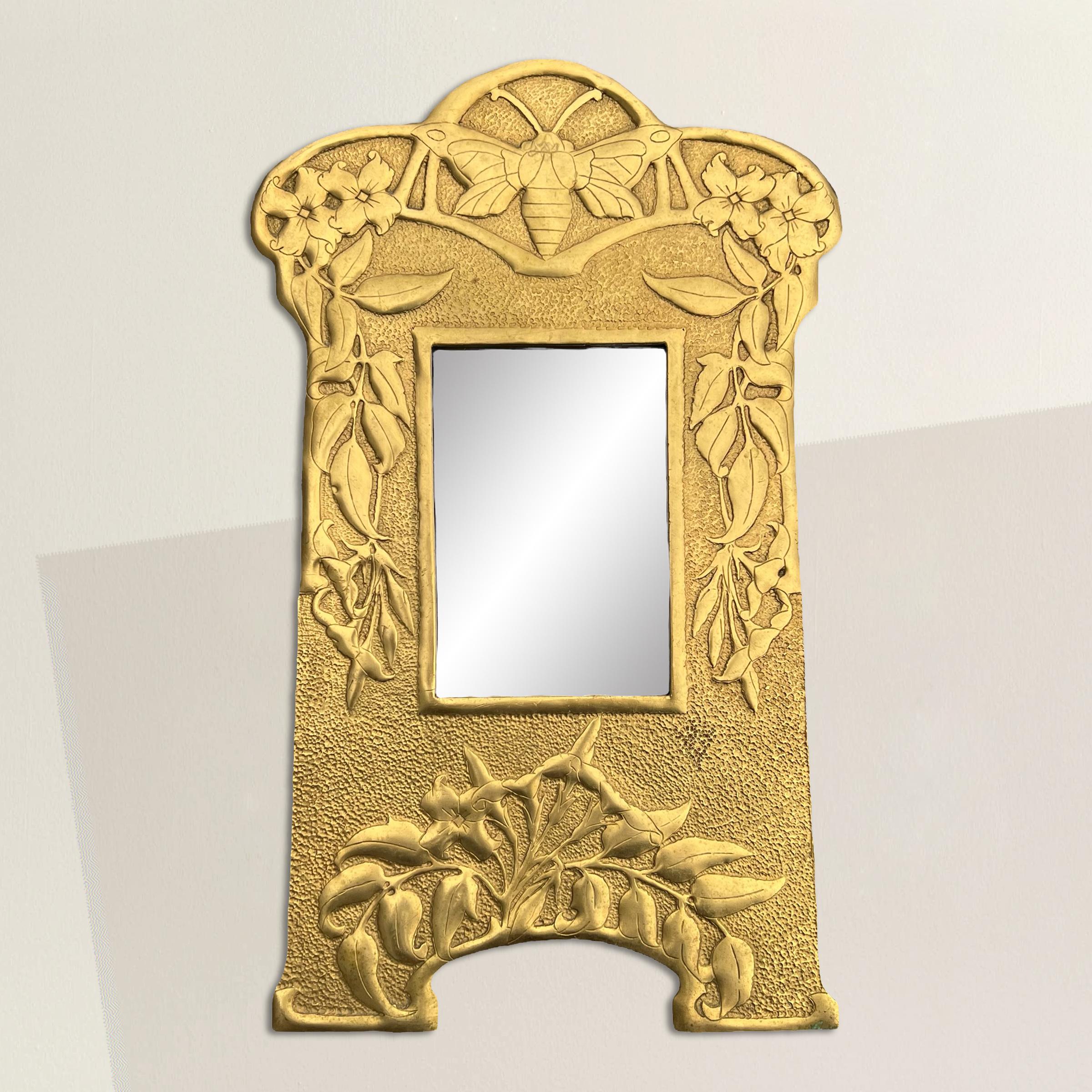 Ce miroir en laiton de style Art nouveau anglais du début du XXe siècle est un véritable régal pour les yeux, car il est orné d'un décor repoussé complexe. Au sommet, une abeille majestueuse symbolise l'industrie, la diligence et la communauté,