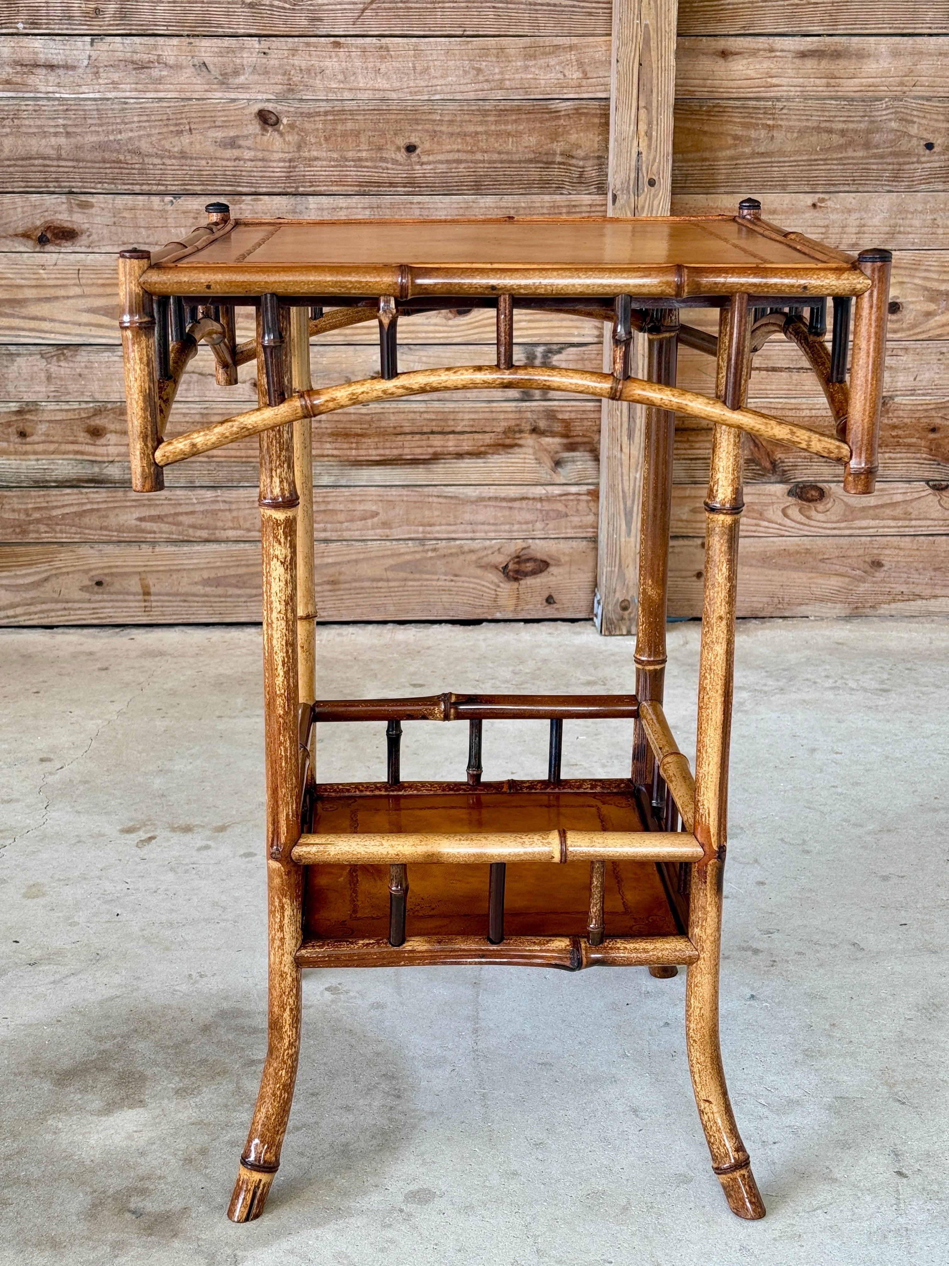 Bel exemple de l'artisanat anglais du bambou, cette table d'appoint de la fin du XIXe siècle ou du début du XXe siècle présente un plateau en cuir gaufré et une structure en bambou dans une finition bicolore magnifiquement vieillie. La qualité de la