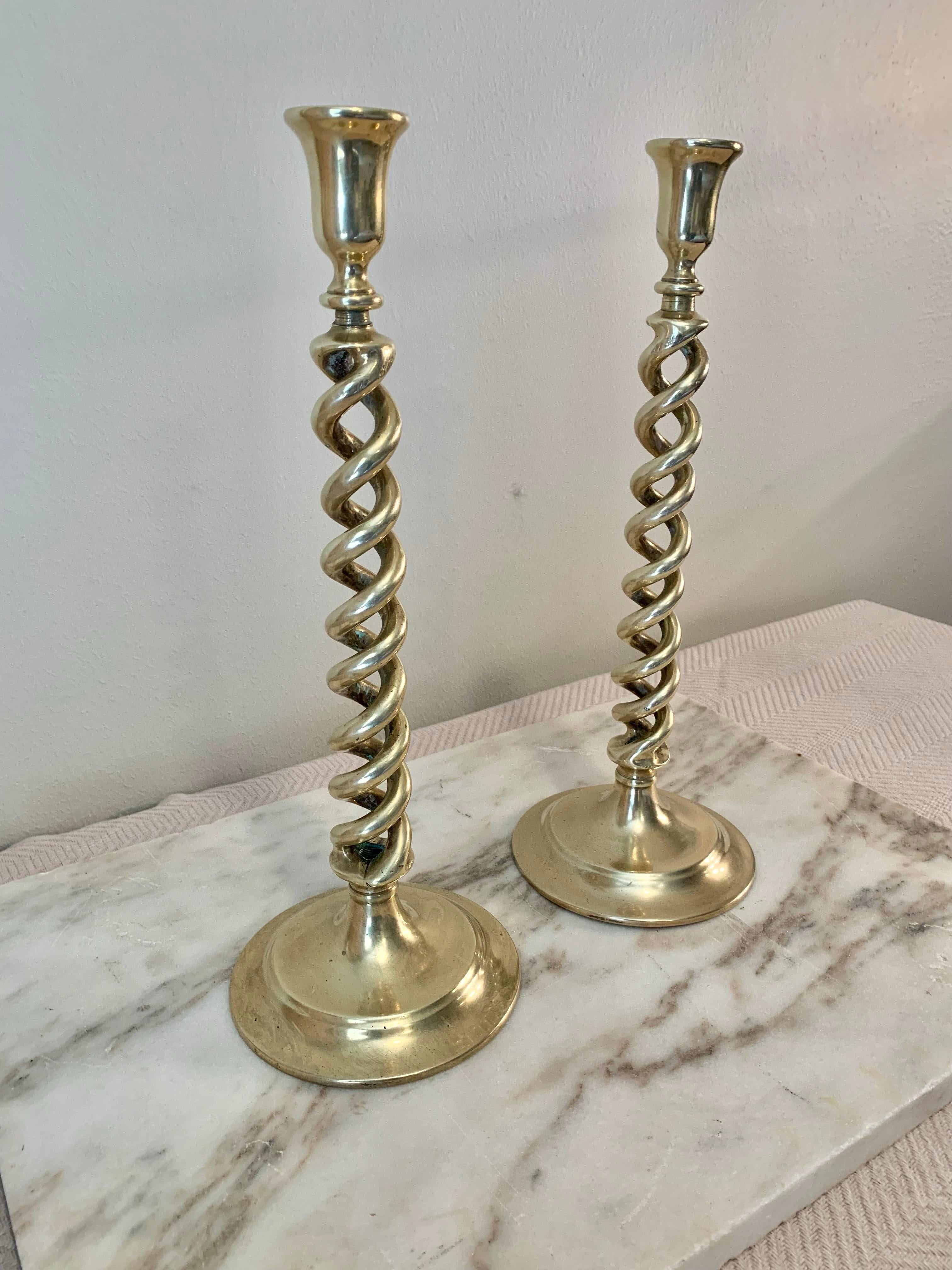 Found in England, this pair of Brass Barley Twist Candlesticks were handcrafted in the early 1920's by English Artisans. Each candlestick features a double twist body or open barley twist that rest below the candle holder and finished with a round