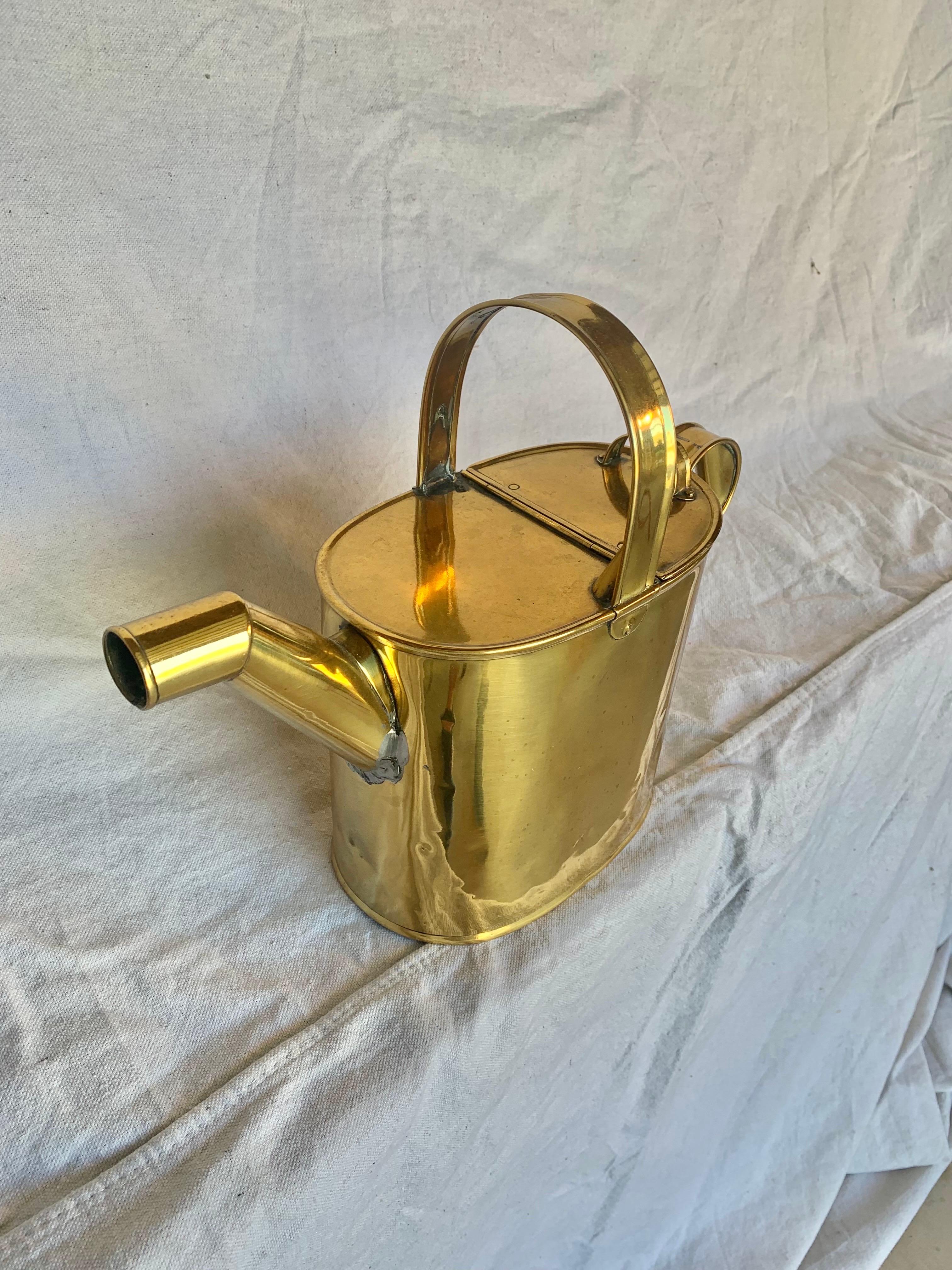 Trouvé en Angleterre, cet arrosoir de jardin du début du XXe siècle a été fabriqué par des artisans en laiton au début des années 1900. La pièce présente trois poignées aux détails complexes reposant au-dessus d'une canette ovale. Deux poignées