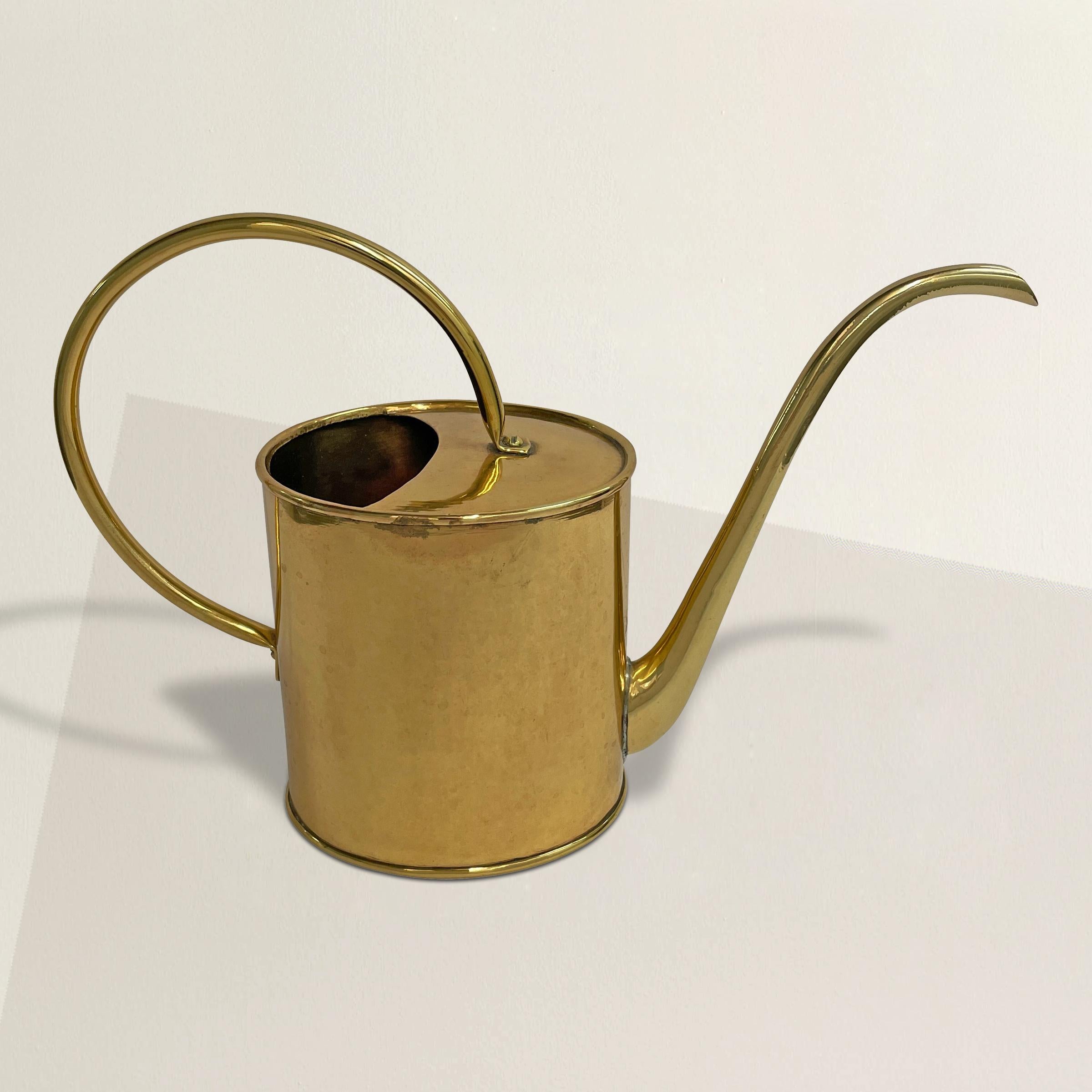 A faithful and hardworking vintage English brass watering can with a large round handle and a mirrored polished finish. Perfect for watering house plants, or smaller planters on your patio.