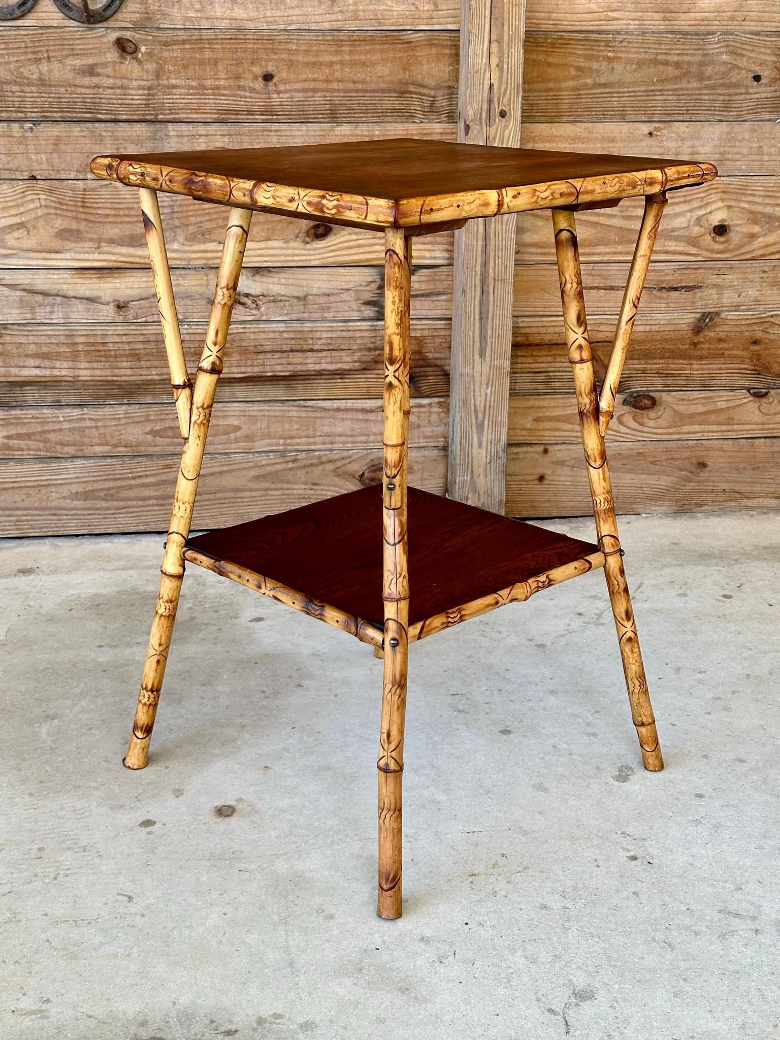 This beautiful antique English burnt bamboo side or center table features a rich Walnut top and a lower shelf, blending elegance and functionality. The table showcases a unique combination of burnt bamboo and walnut, both of which have been