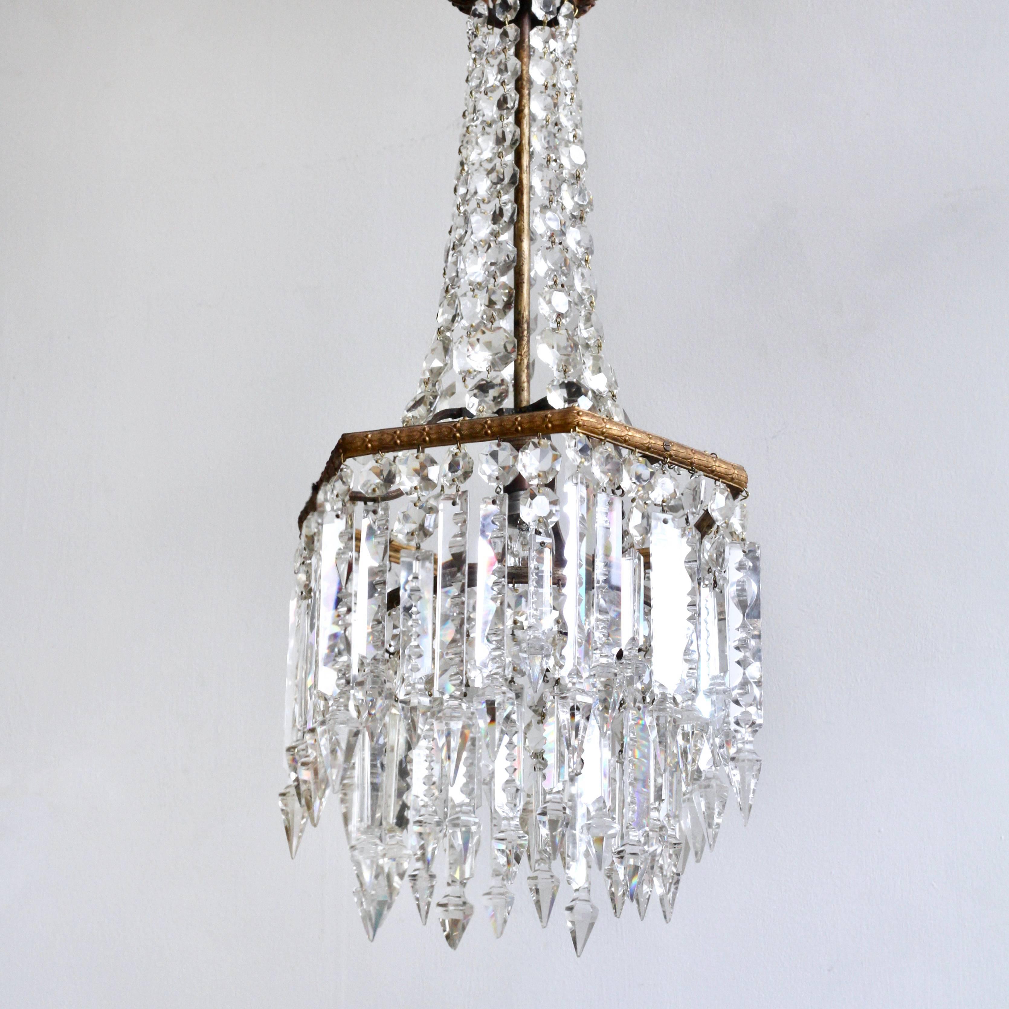 A stunning example of an English crystal waterfall chandelier. The cast gilt brass upper frame is hexagonal with a lower circular frame adjoined with chain. The upper gilt coroner forms the upper section of the chandelier with swags of handcuff