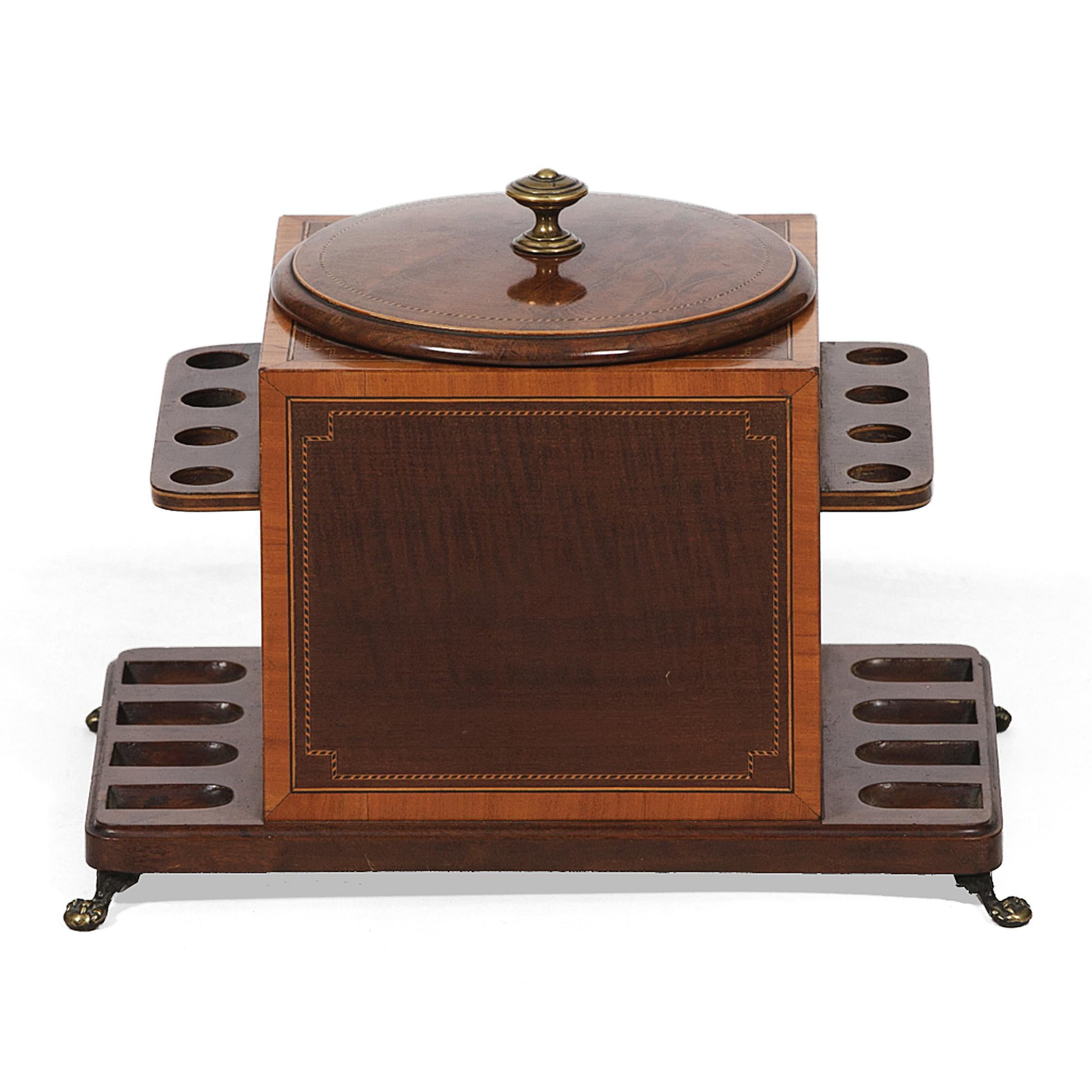 The tobacco compartment housed in an inlaid mahogany and satinwood case, flanked by two pipe racks, and with brass paw feet. The weighted lid stamped “Dunhill, London / The White Spot / Pat. No. 11832 / 13.”