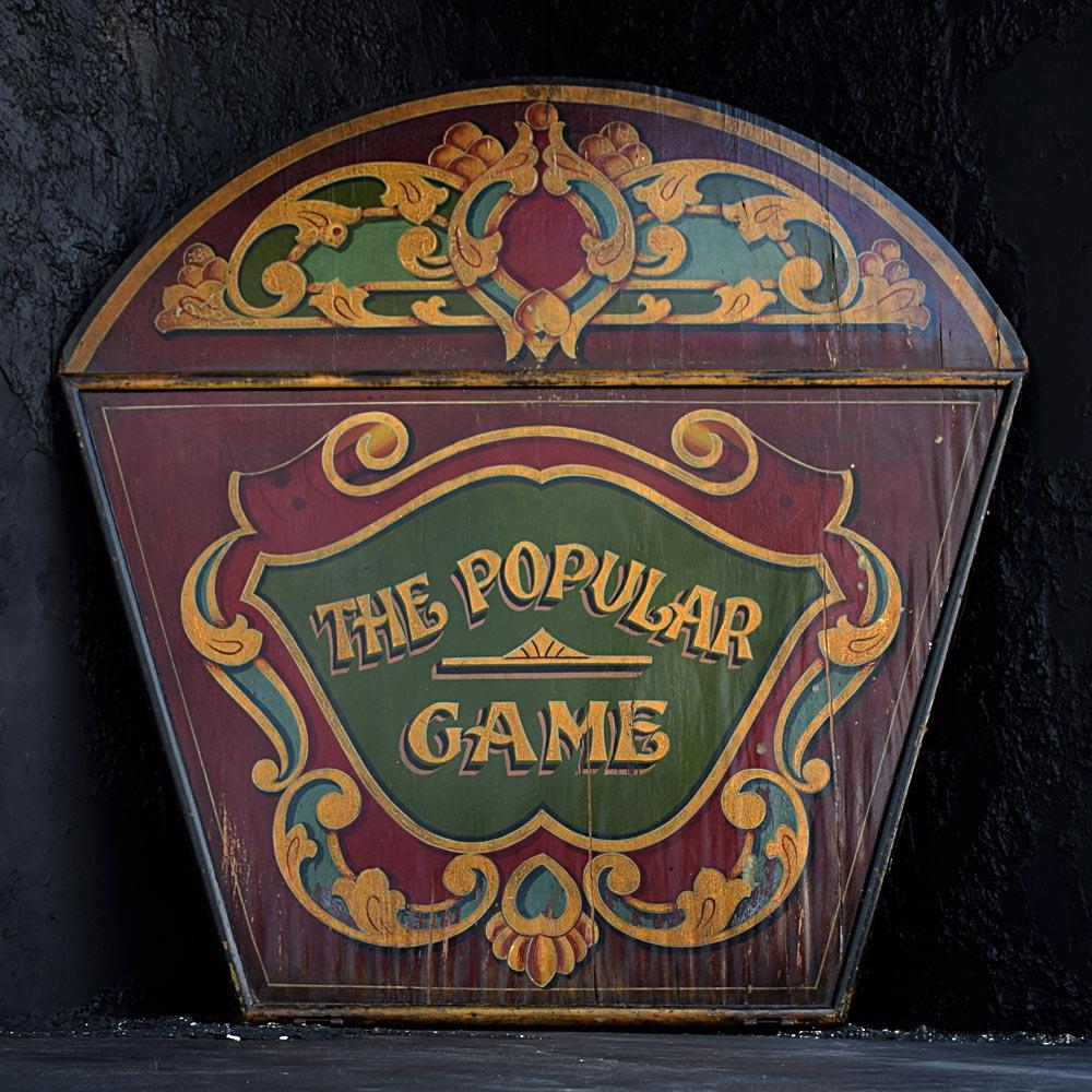English Fairground Carousel panel 
We are proud to offer a wonderful example of an early 20th century English fairground panel. From a fairground carousel ride, with the hand painted graphic “The Popular Game”. A wonderful, aged patination and