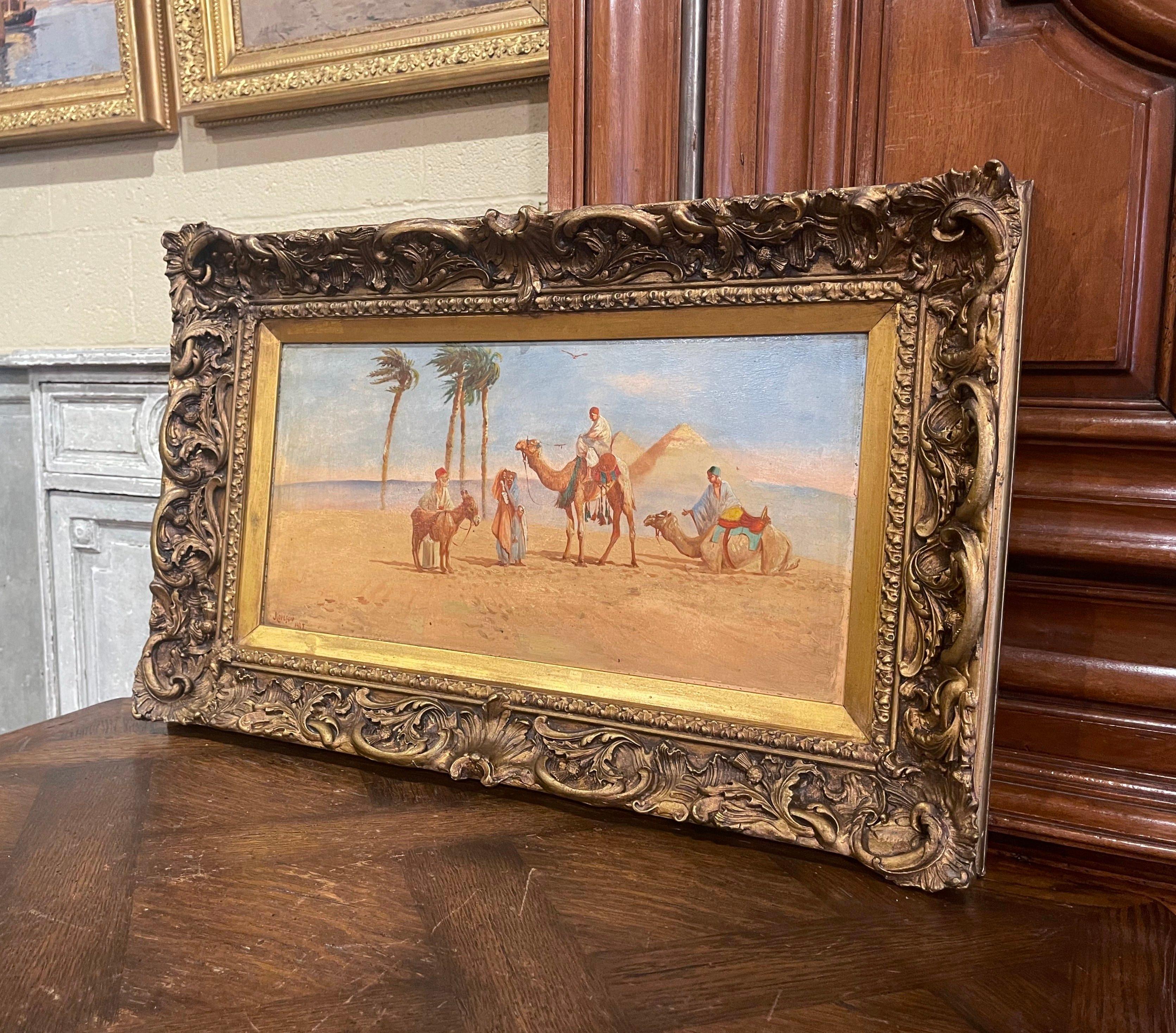 Decorate an office or study with this colorful antique painting. Created in England and set in the original ornate and carved gilt wood frame, the artwork painted on board depicts an Arab encampment in desert behind the Giza pyramid together with