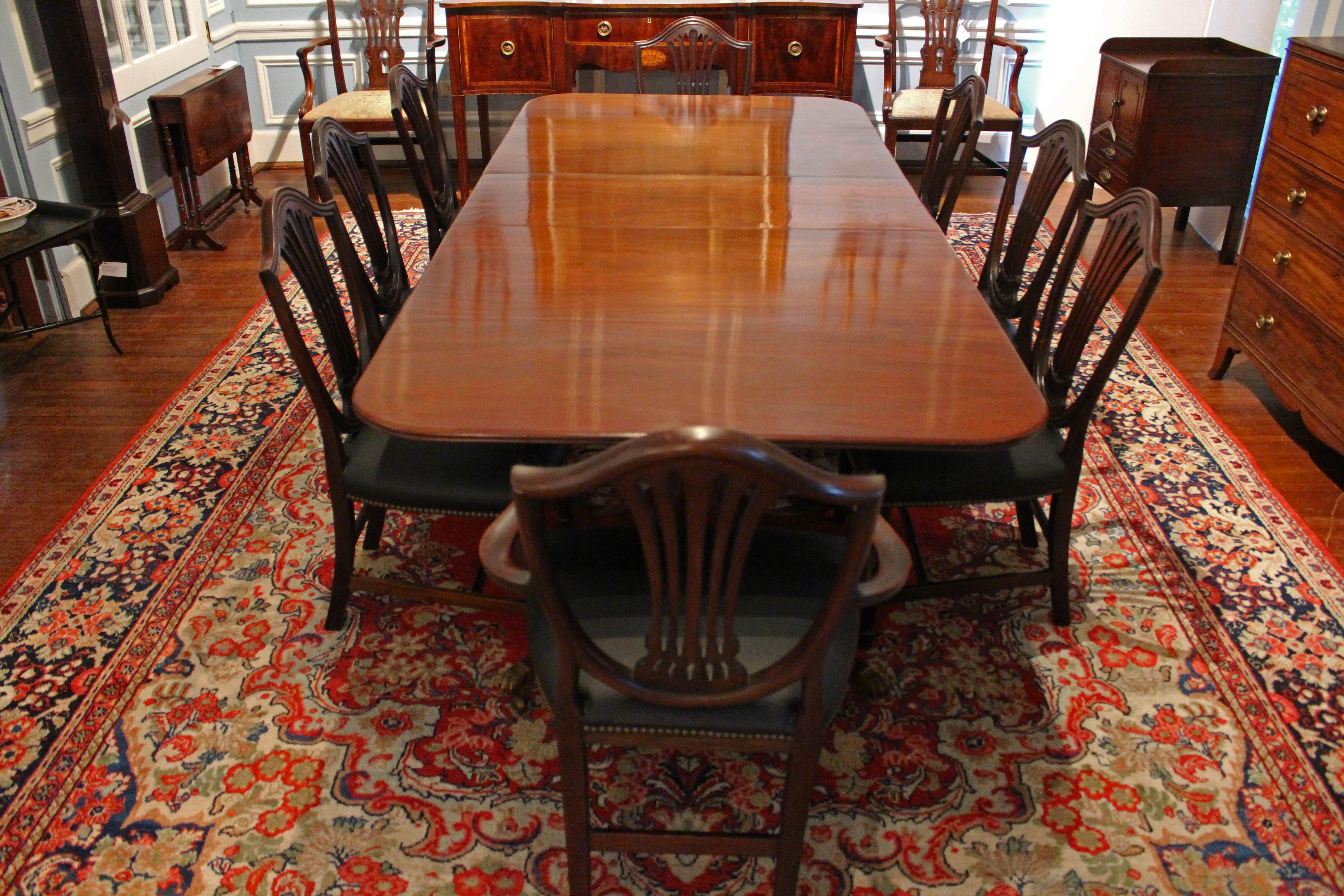 Early 20th century English George III style double pedestal extending dining table with one leaf. Each pedestal with 4 outswept, reeded legs ending in lion paw brass caps & casters. 
29