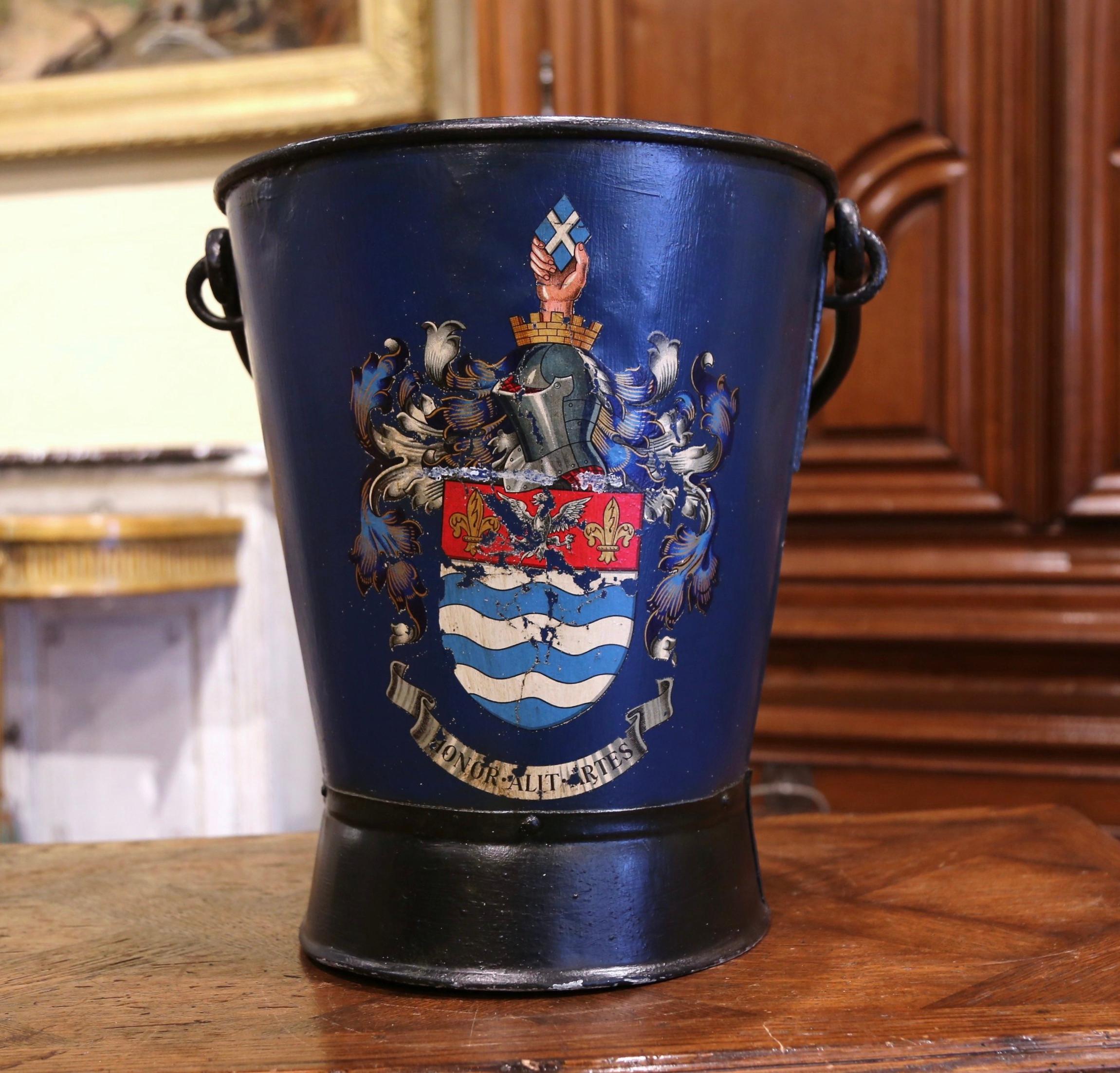 Place this large, colorful antique stand at your front door or in your mudroom to collect umbrellas, canes or other accessories. Created in England, circa 1920, the iron bucket with top and side handles, is decorated with a coat of arms with eagle