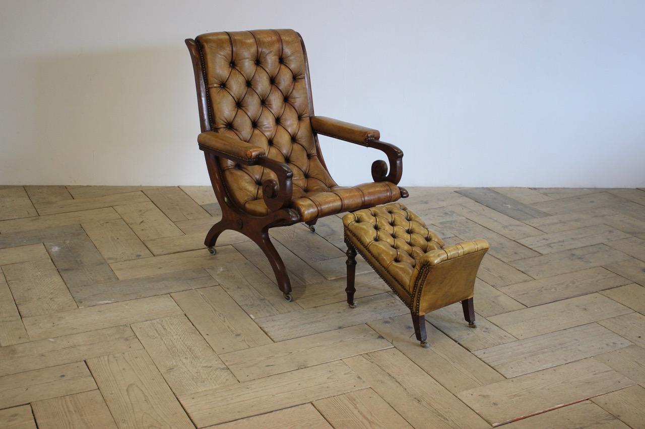 An early 20th century English library chair and foot stool, retaining the original deep buttoned leather with horsehair upholstery and castors on a mahogany frame. 
Measurements: 

Chair: 101cm high x 70cm wide x 82cm deep x 42cm high ( floor to