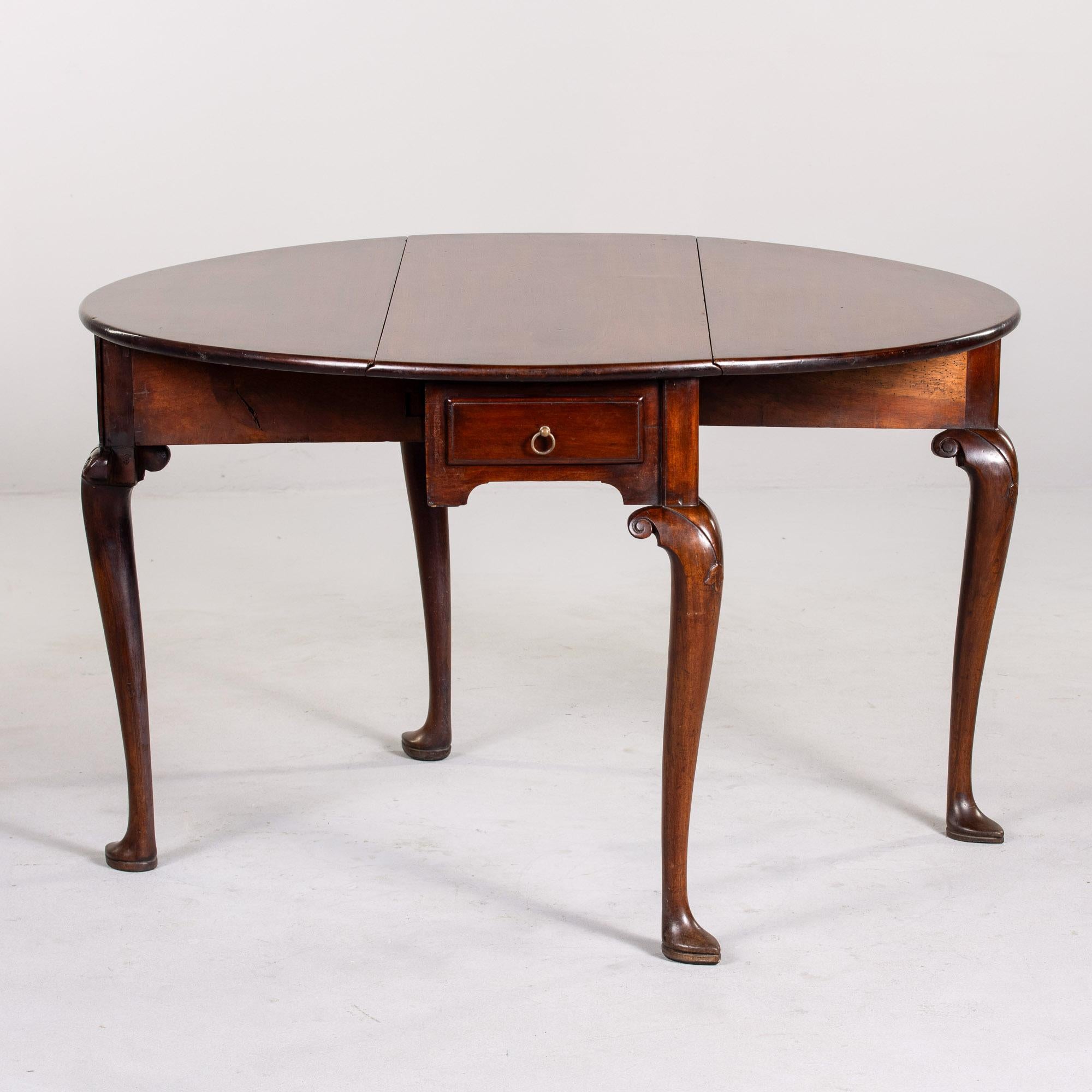 Trouvée en Angleterre, cette table à abattant en acajou date des années 1930. Plateau ovale (lorsque les feuilles sont déployées), pieds en cabriole et petit tiroir central fonctionnel. Avec les deux feuilles abaissées, le plateau de la table mesure
