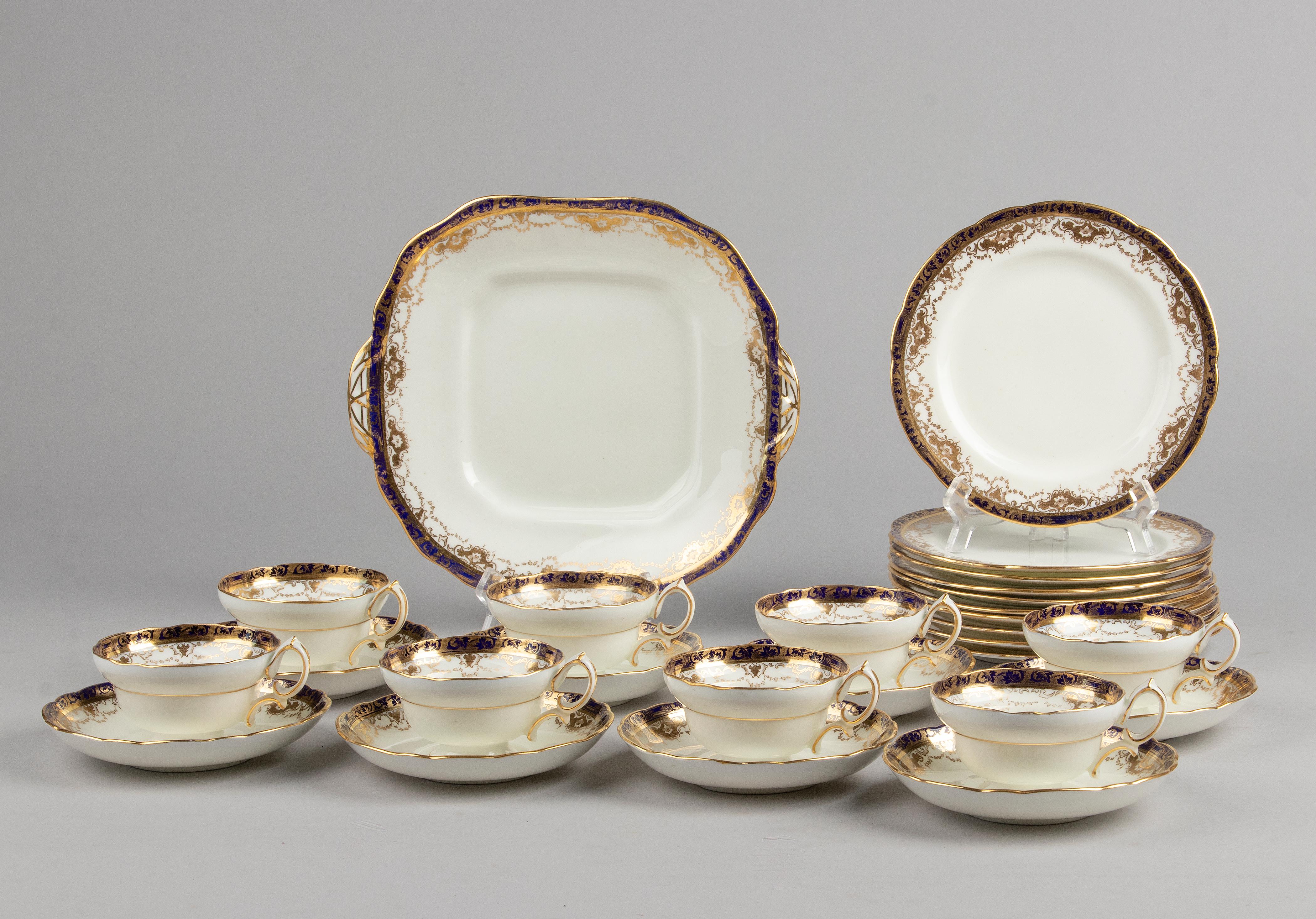Lovely English porcelain tea set made by Hammersley. The service is beautifully decorated with cobalt blue edges and gold accents. The service dates from circa 1920 and is in very good condition. De composition of the set is as follows: 10 cake