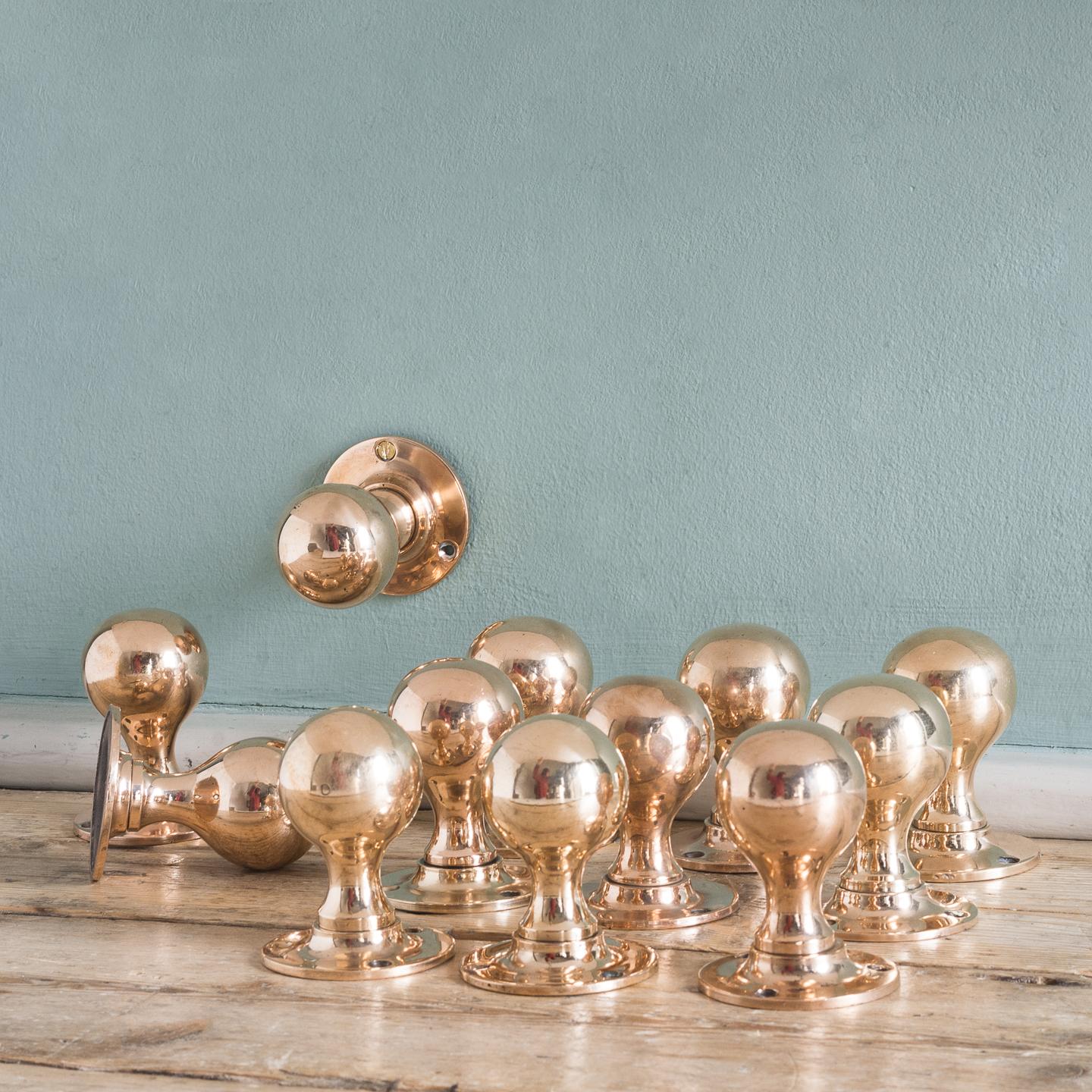 Early 20th century rose brass door knobs, on turned backplates.
