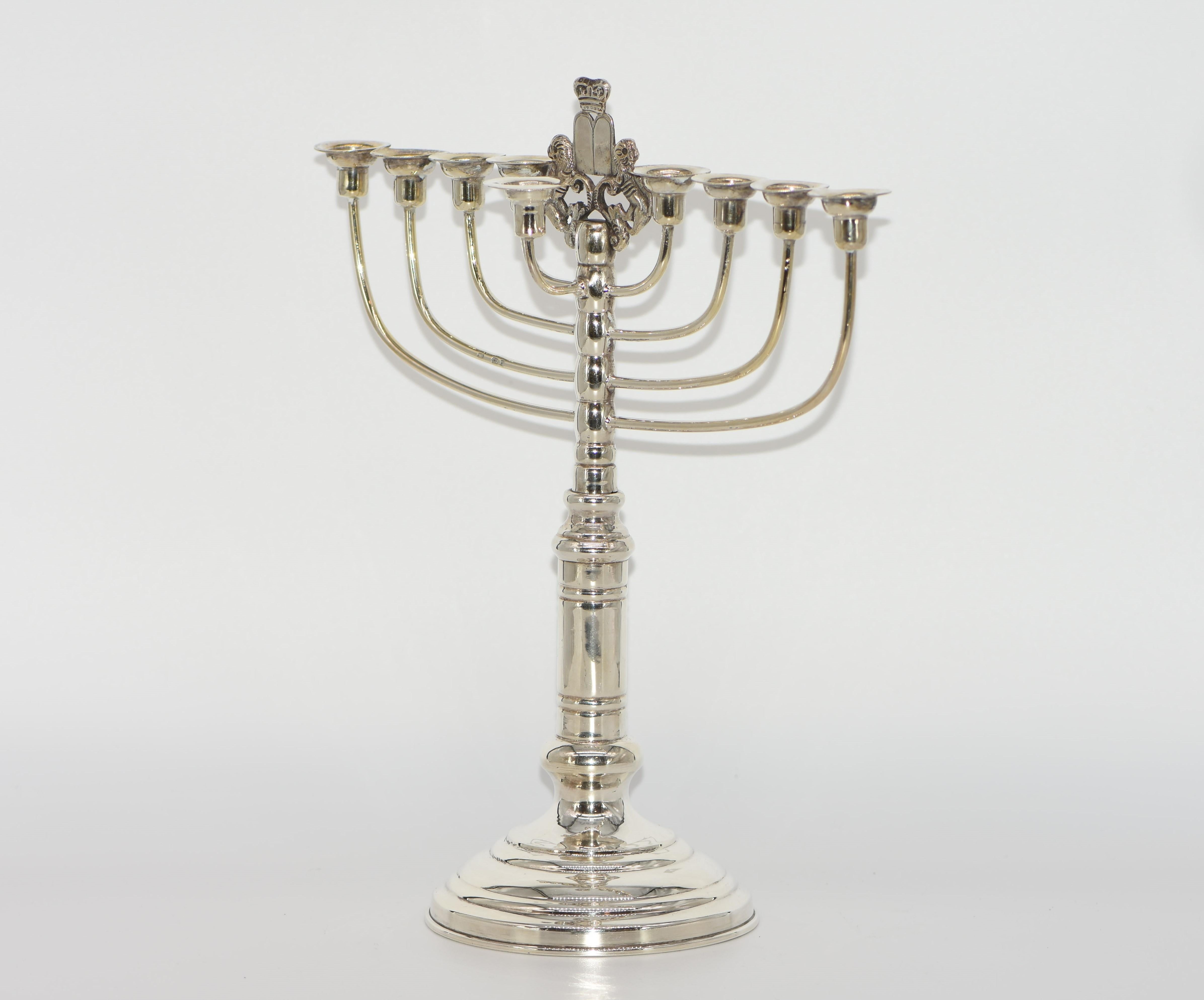 Standing Hanukkah lamp made in London, England, 1926. Stamped and marked with English silver hallmarks for 1926, London. In the center stands the “Lion of Judah,” a pair of recumbent lions raised on pedestals, carrying the Ten Commandments, topped