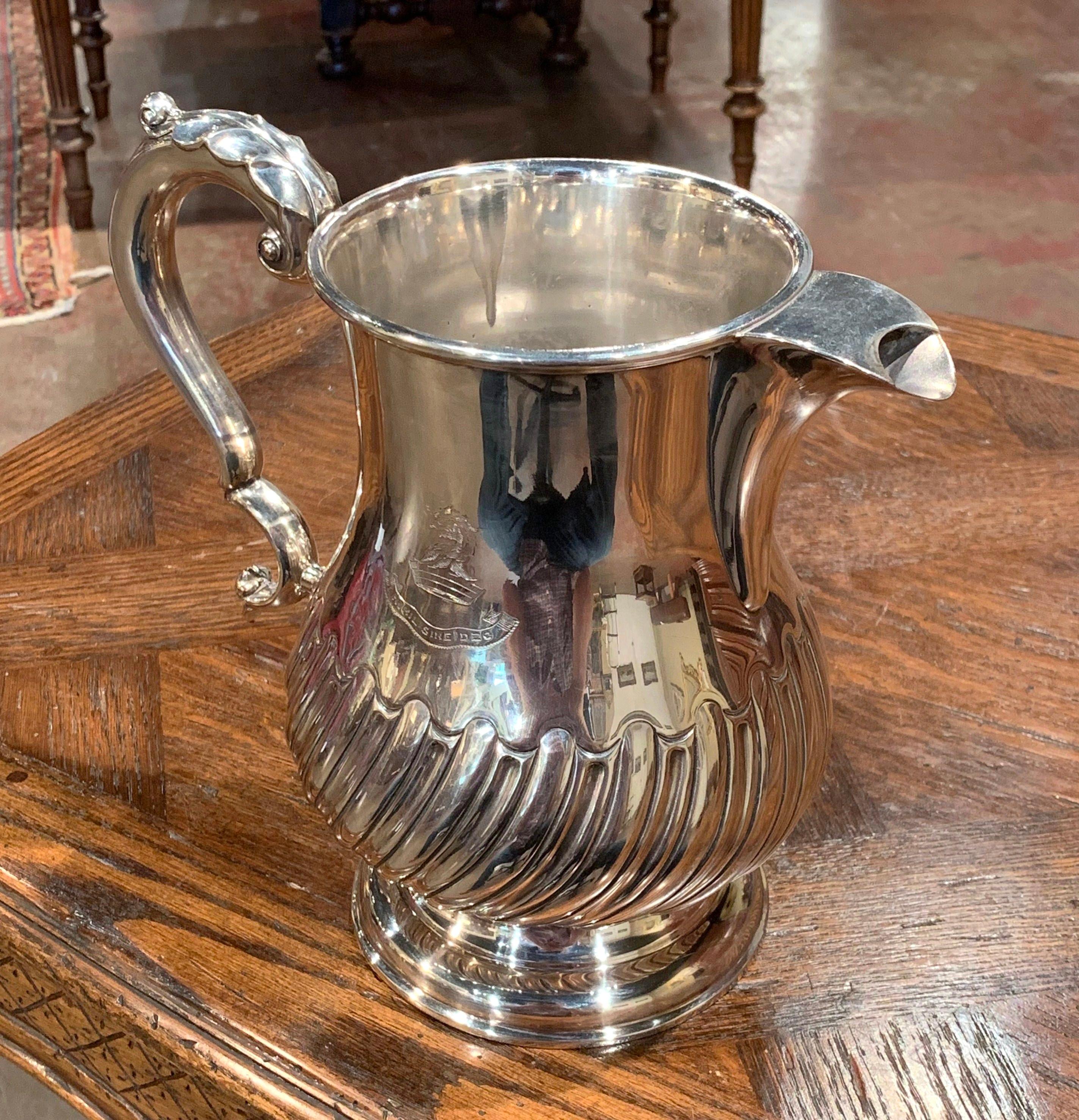 Decorate a wet bar with this elegant, antique silver plated pitcher. Crafted in England circa 1920, the traditional, timeless water jug sits on a raised rounded base. The pitcher has a baluster form and a downward sweeping ribbing on the lower half