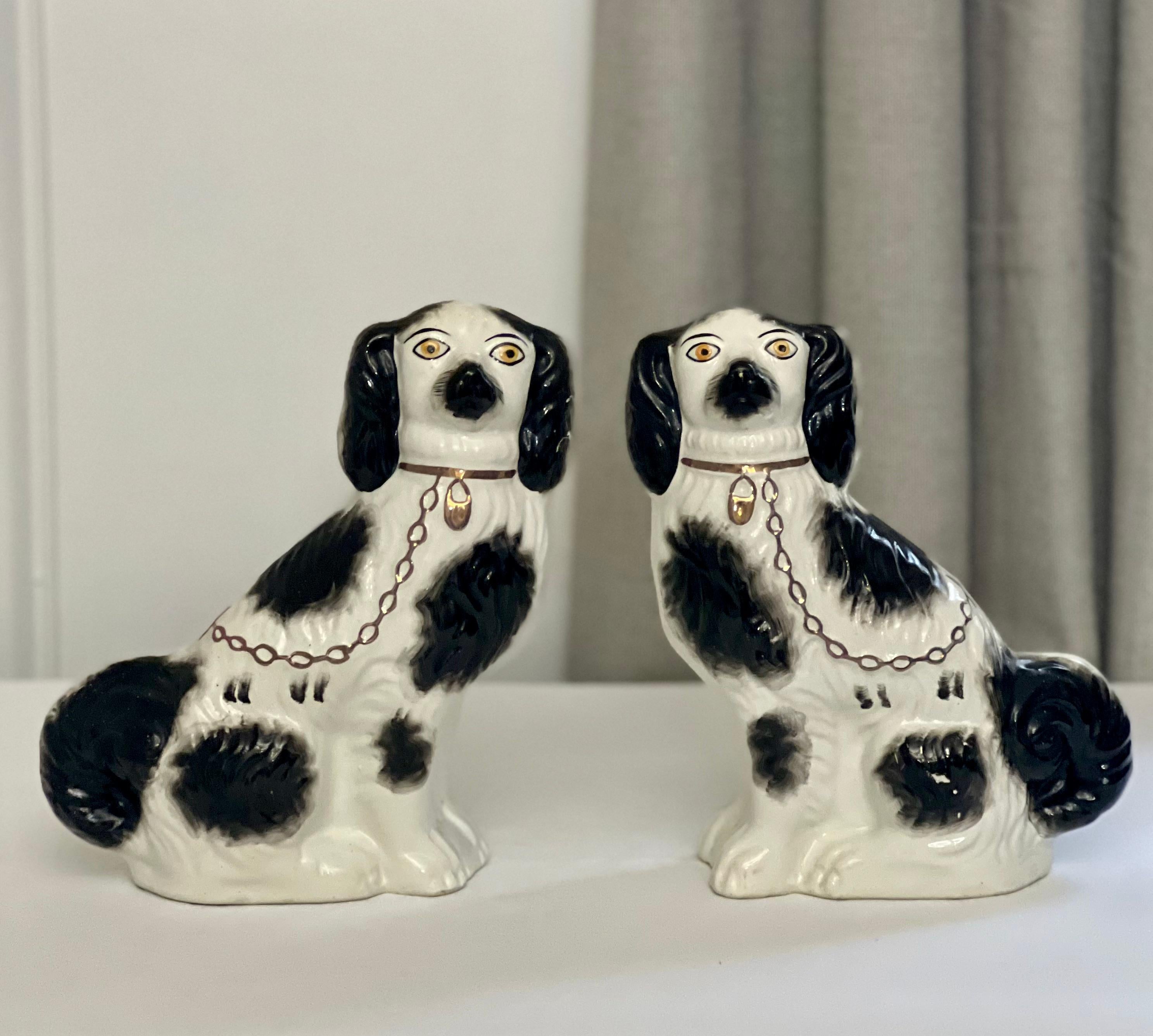 Facing pair of Staffordshire spaniel figurines, England, c. 1920.

Charming hand-painted ceramic King Charles Cavalier Spaniels in black and white paint decoration with a gilt collar and chain. With faces full of character and sweet expression, the