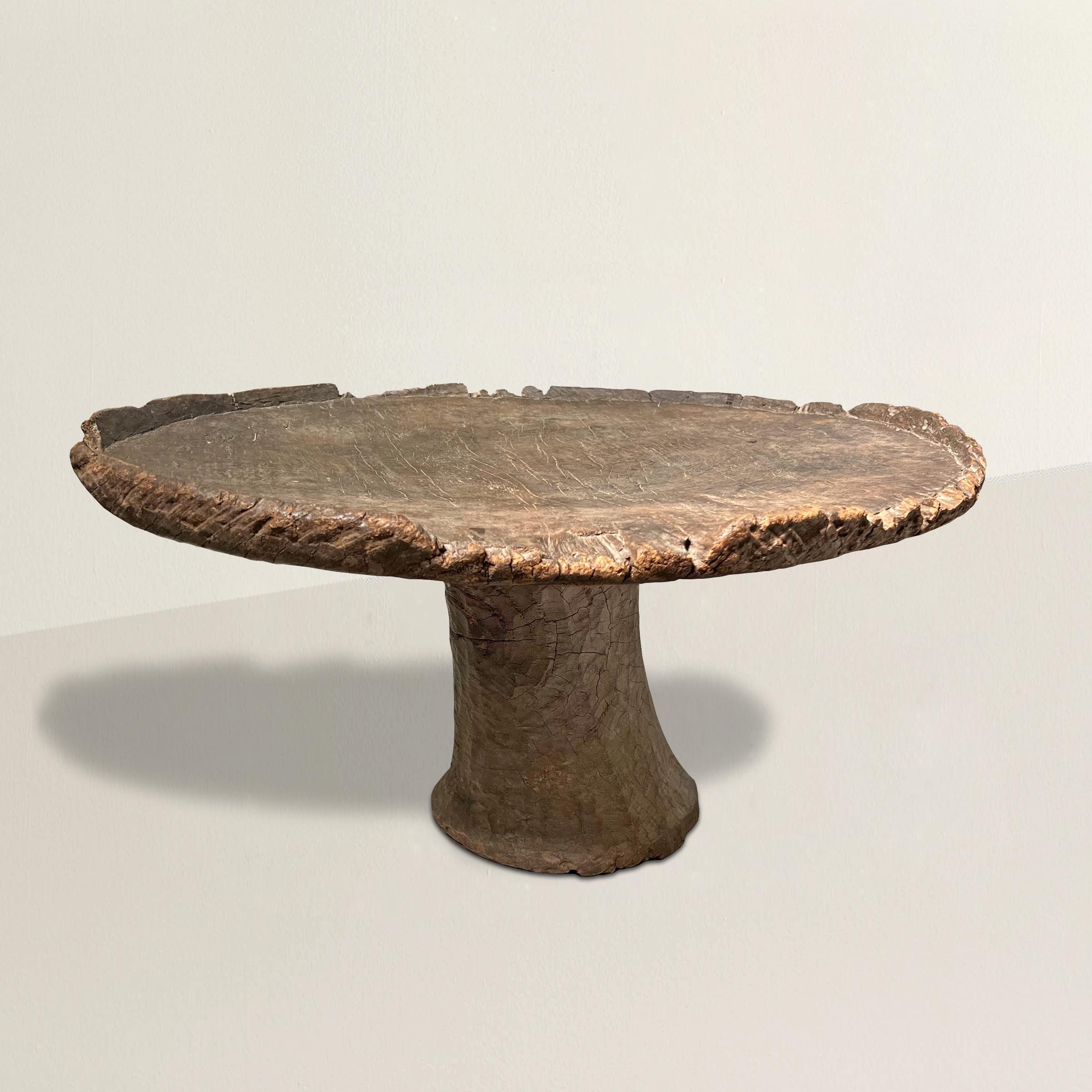 A rare and alluring Wabi-Sabi early 20th century Ethiopian table carved of one piece of wood with a round top with simple rim supported by a pedestal base. Originally used to serve food, this is the perfect cocktail table in your chic city apartment