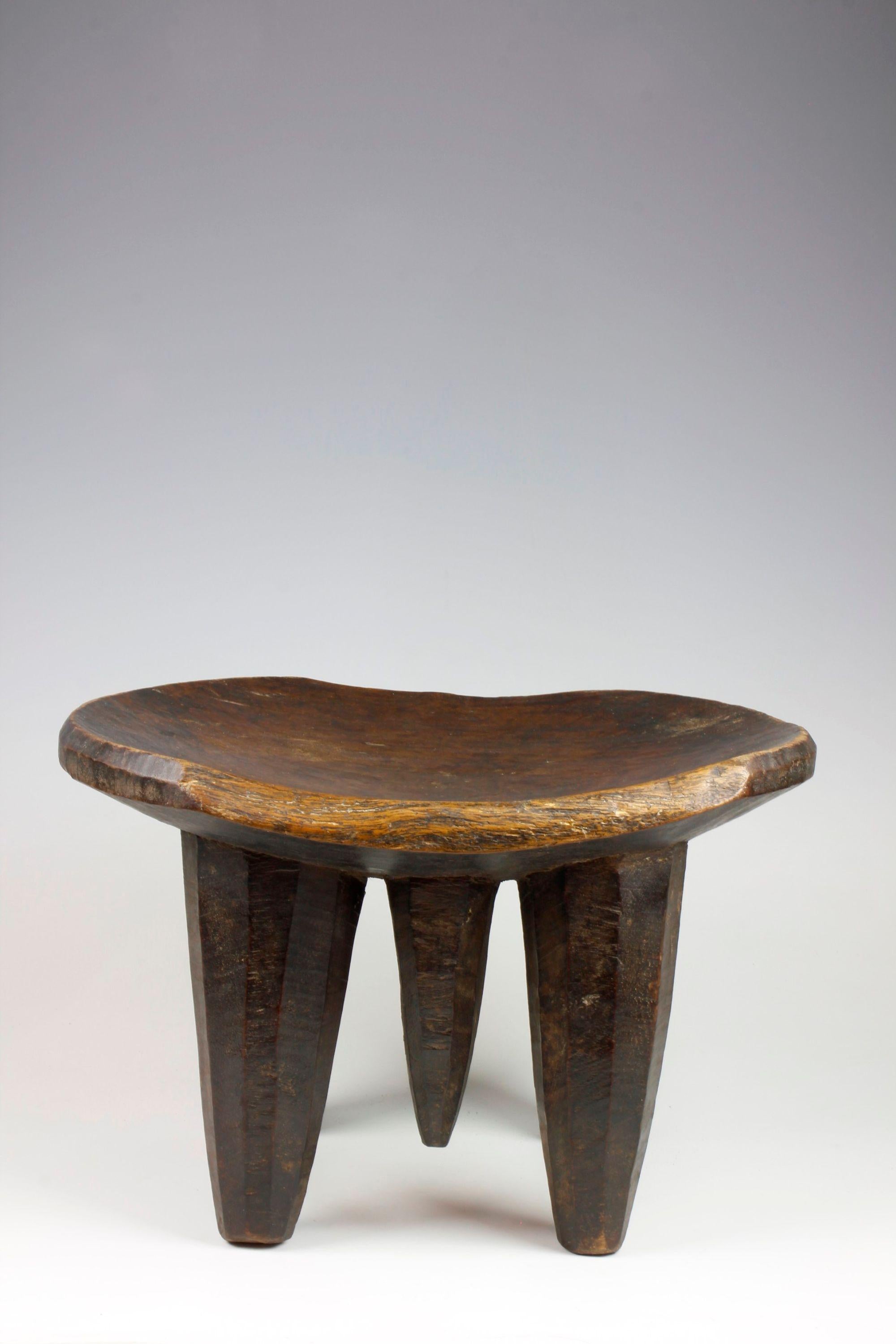 Finely carved from a single piece of wood, this stool from the Sidamo region of Ethiopia displays a wonderful sculptural quality. Four cone-shaped legs support the stool's slightly-curved seat and, located between each front and rear leg, is an