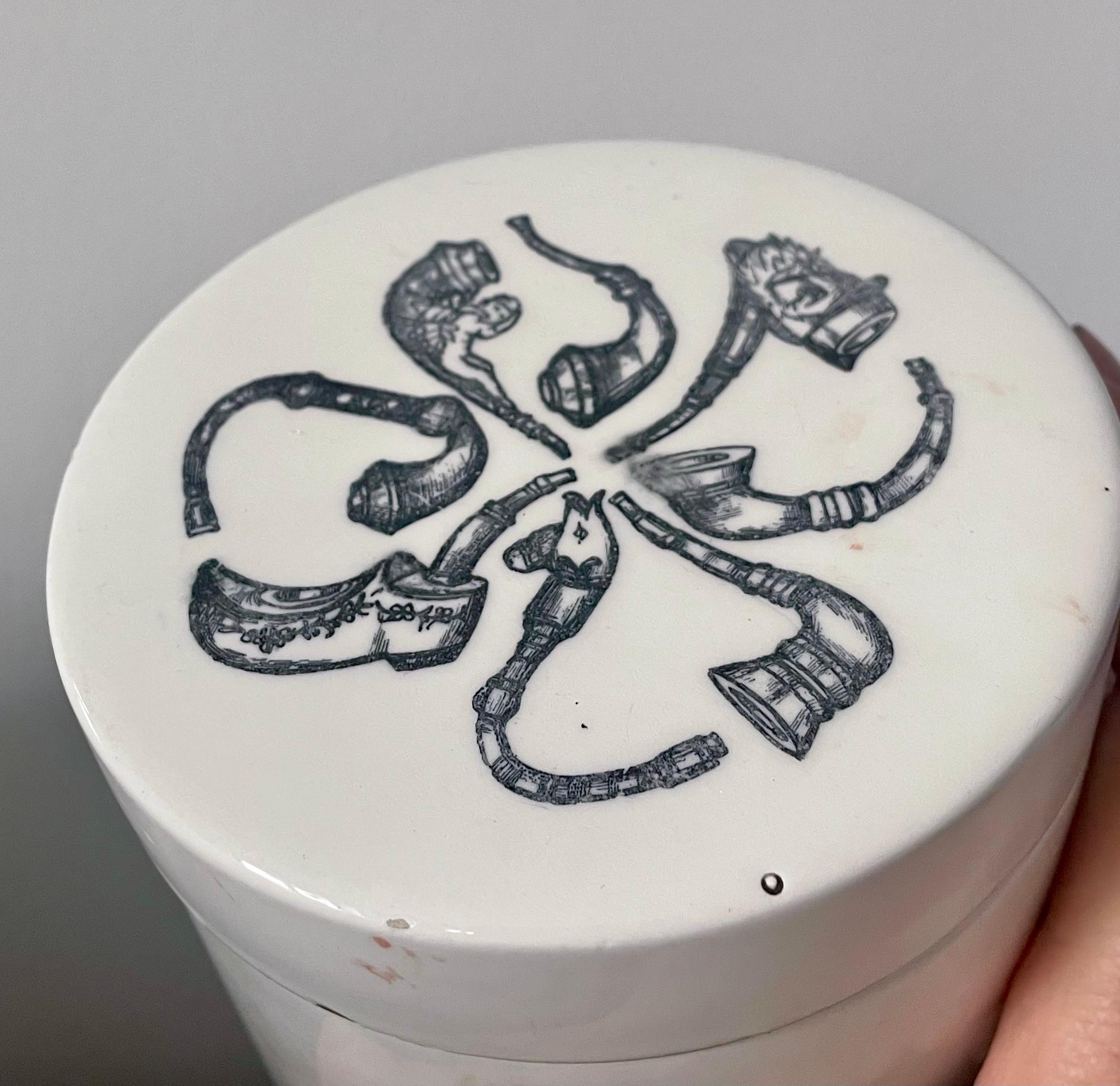 Rare et très décorative jarre à tabac en céramique du début du 20e siècle, probablement d'origine européenne. Cette pièce finement travaillée présente des motifs complexes transférés en noir de pipes assorties, y compris des pipes de caractère et
